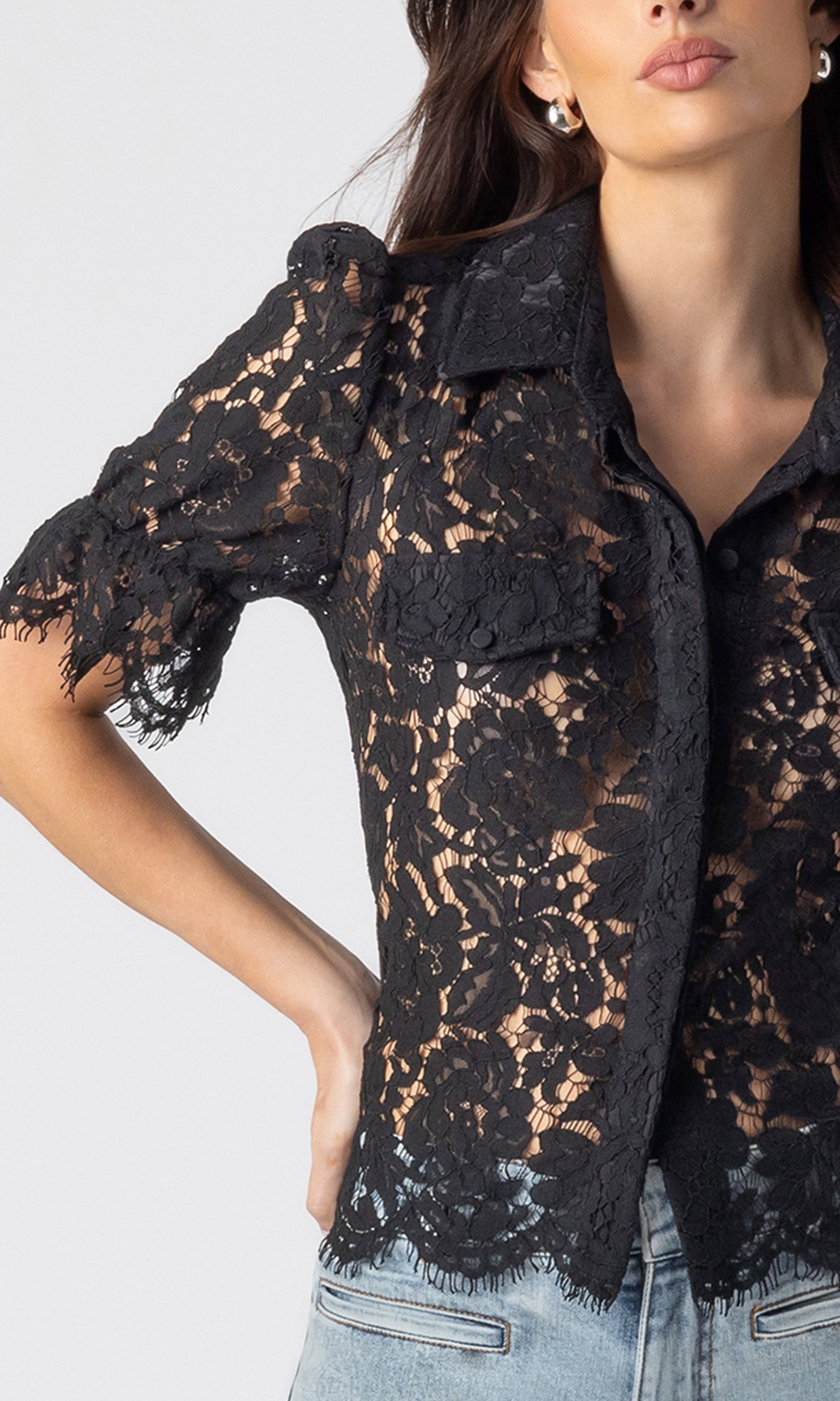 zoomed in image of model wearing the Mina lace shirt showcasing the black lace details all over with a cuffed short sleeve and paired with light blue jeans