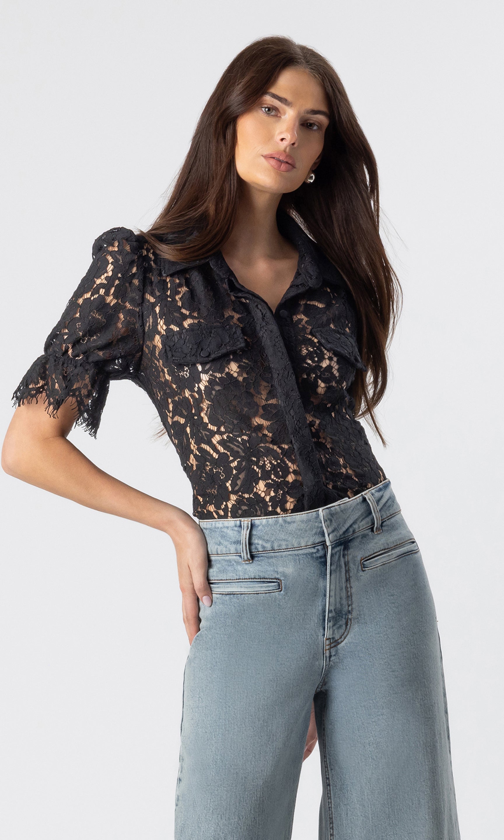 3/4 side view image of model posing wearing the Mina lace shirt in black paired with light blue jeans