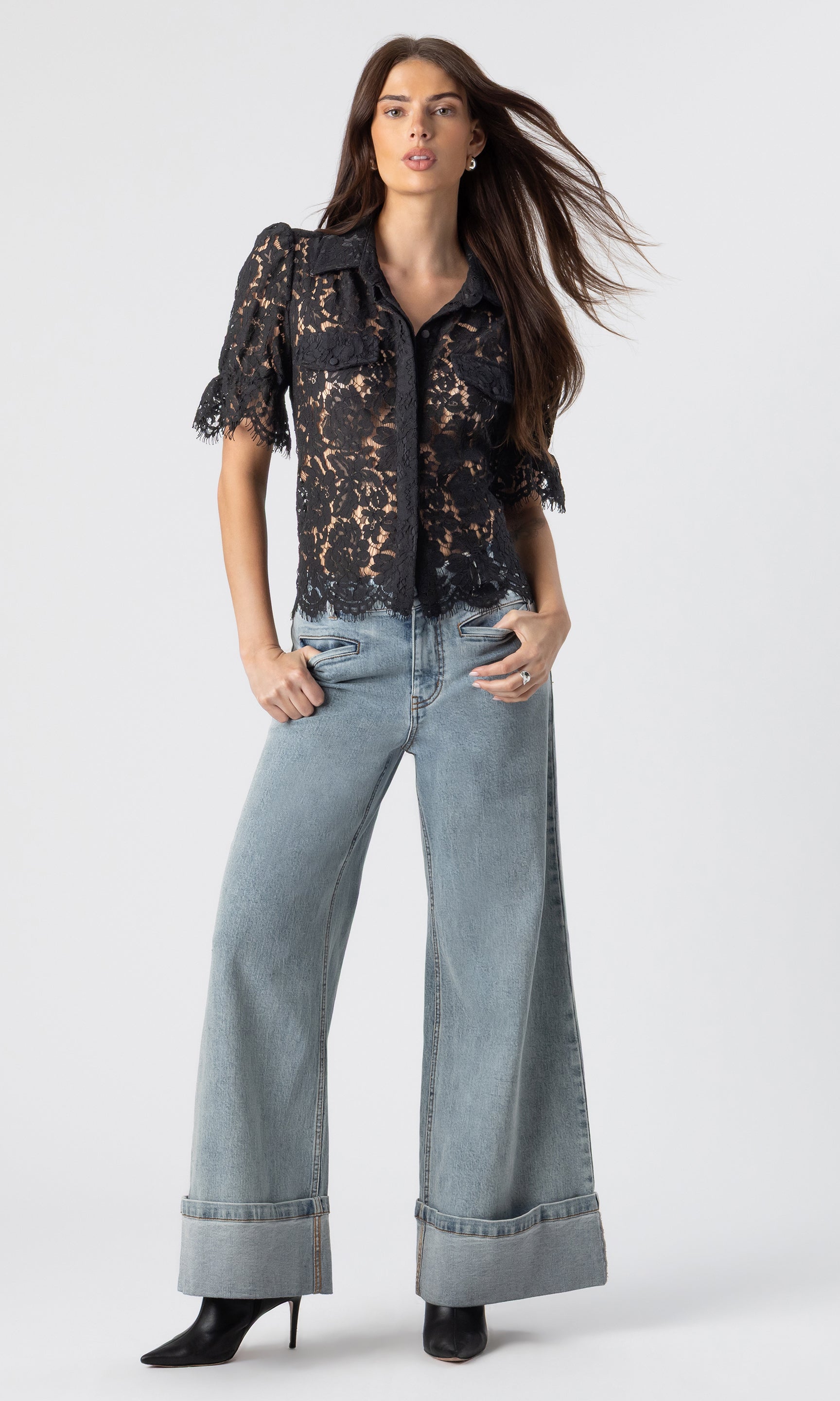 full body image of model posing wearing the Mina lace shirt in black paired with light blue jeans and black heeled booties