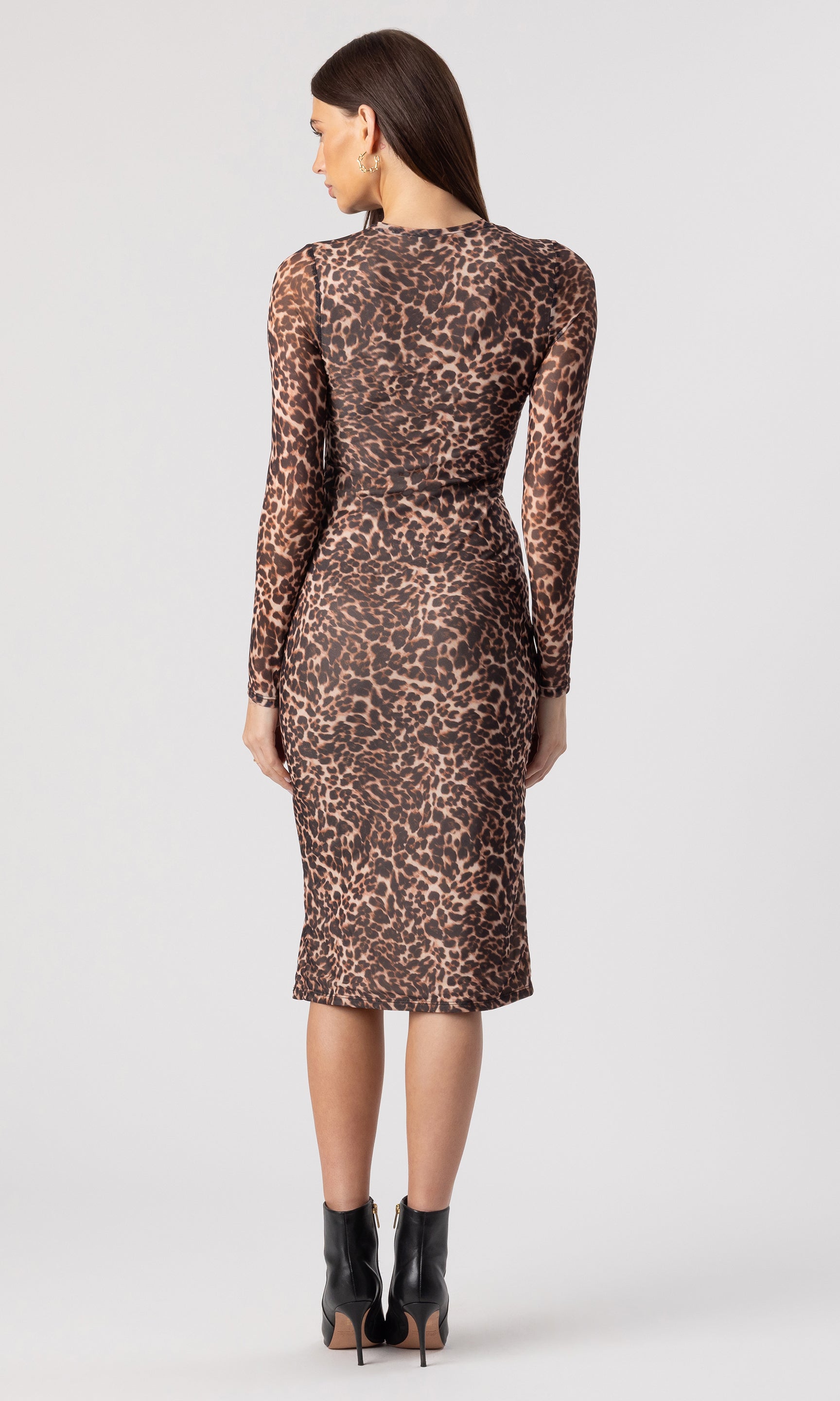 full body back view image of model wearing the Monique Mesh Dress in a leopard print, paired with black heeled booties