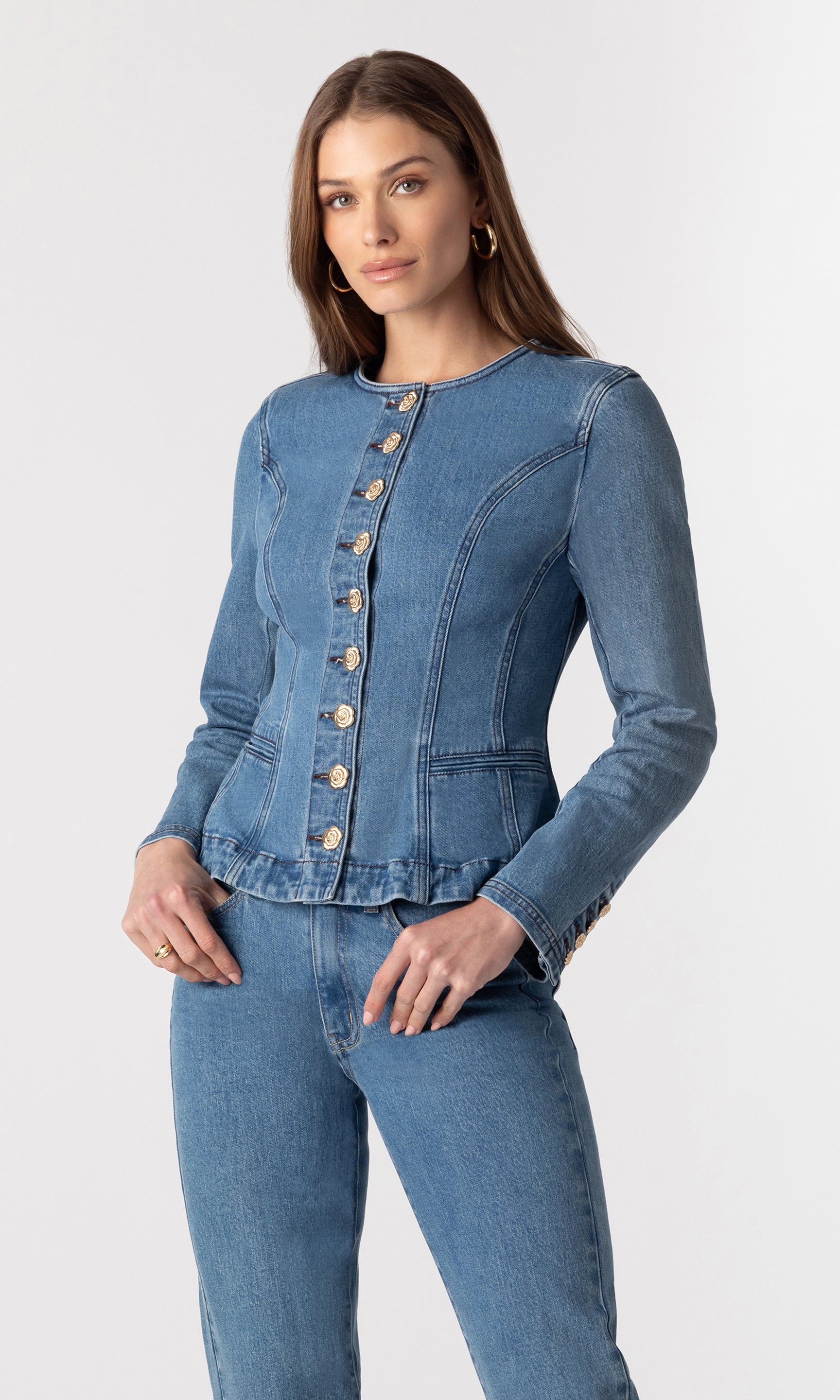 3/4 front view of model wearing the Ophelia blue denim jacket showing the beautiful structure of the jacket with gold buttons down the front, paired with matching blue denim jeans