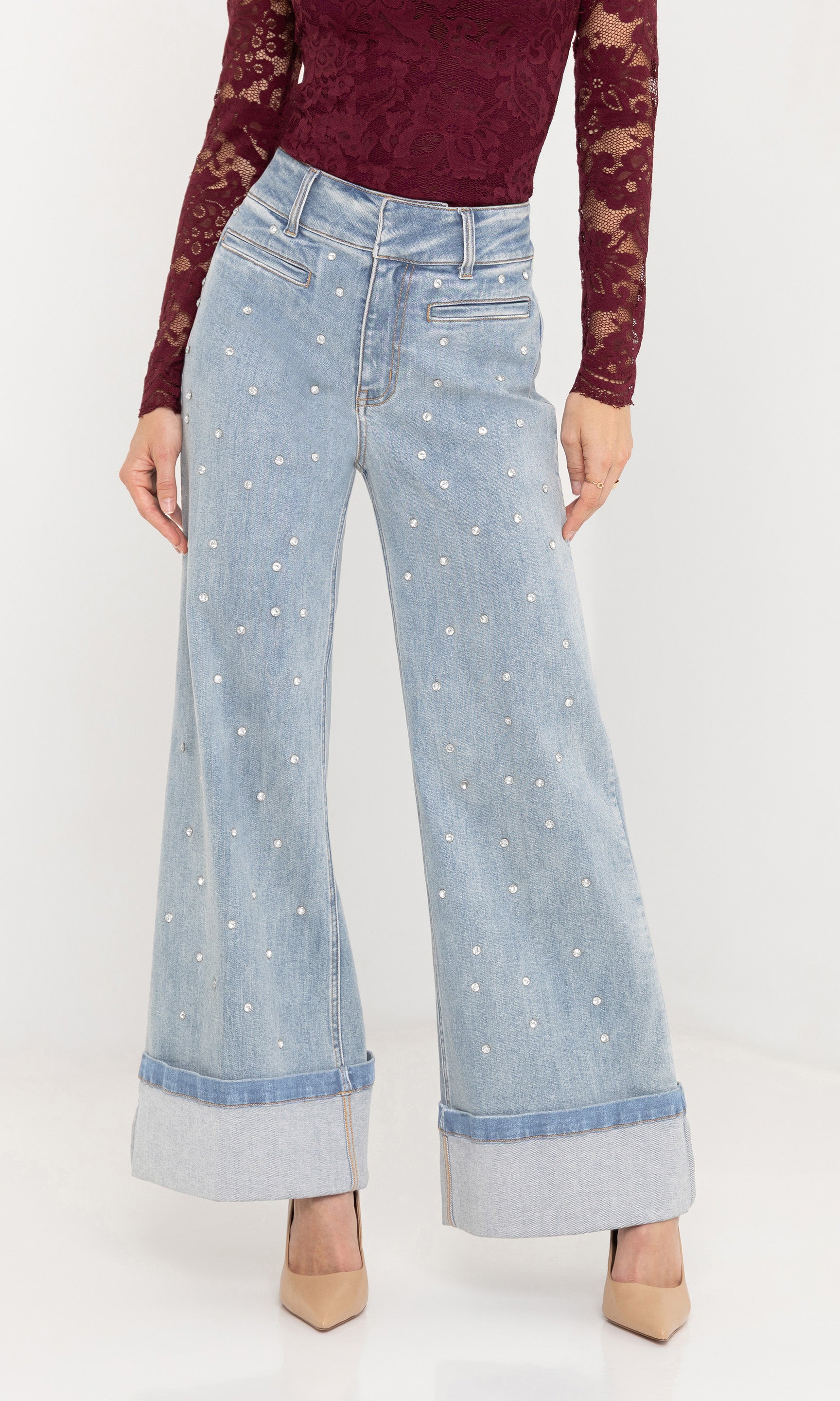 Indoor side view of the Raquel Crystal Stud Jeans paired with a burgundy knit top and nude heels.