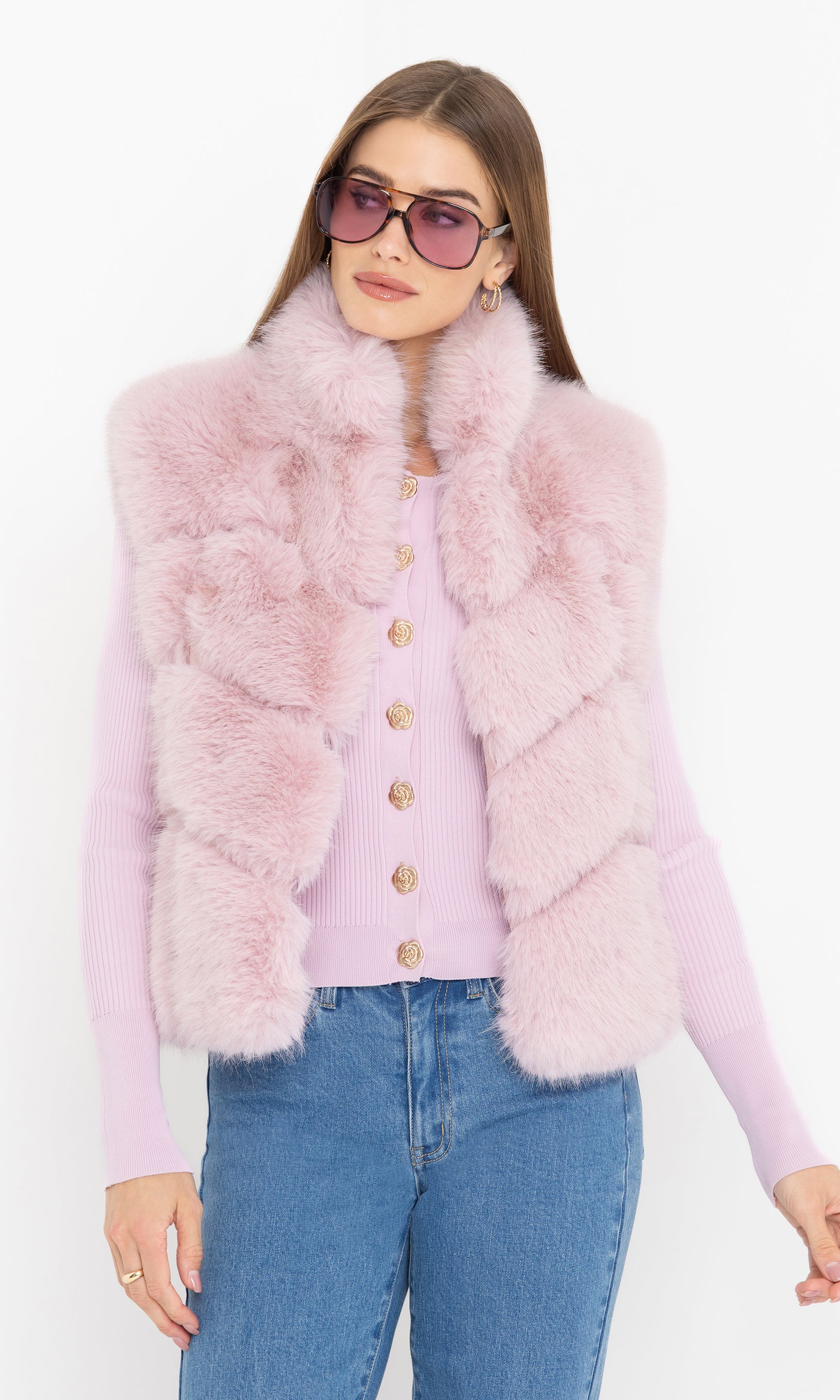 Indoor standing front view of Rosario Faux Fur Vest in blush pink styled with a printed blouse and blue jeans.