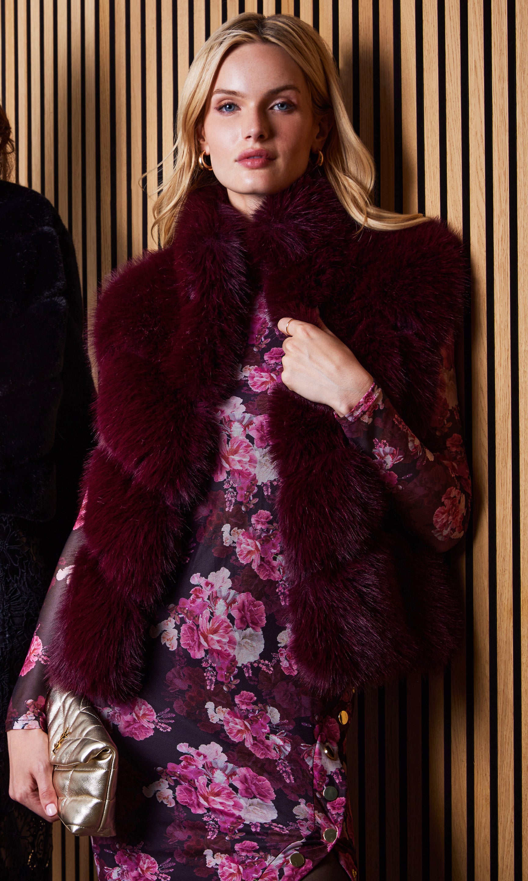 Front view of the rosario faux fur vest layered over a patterned dress.