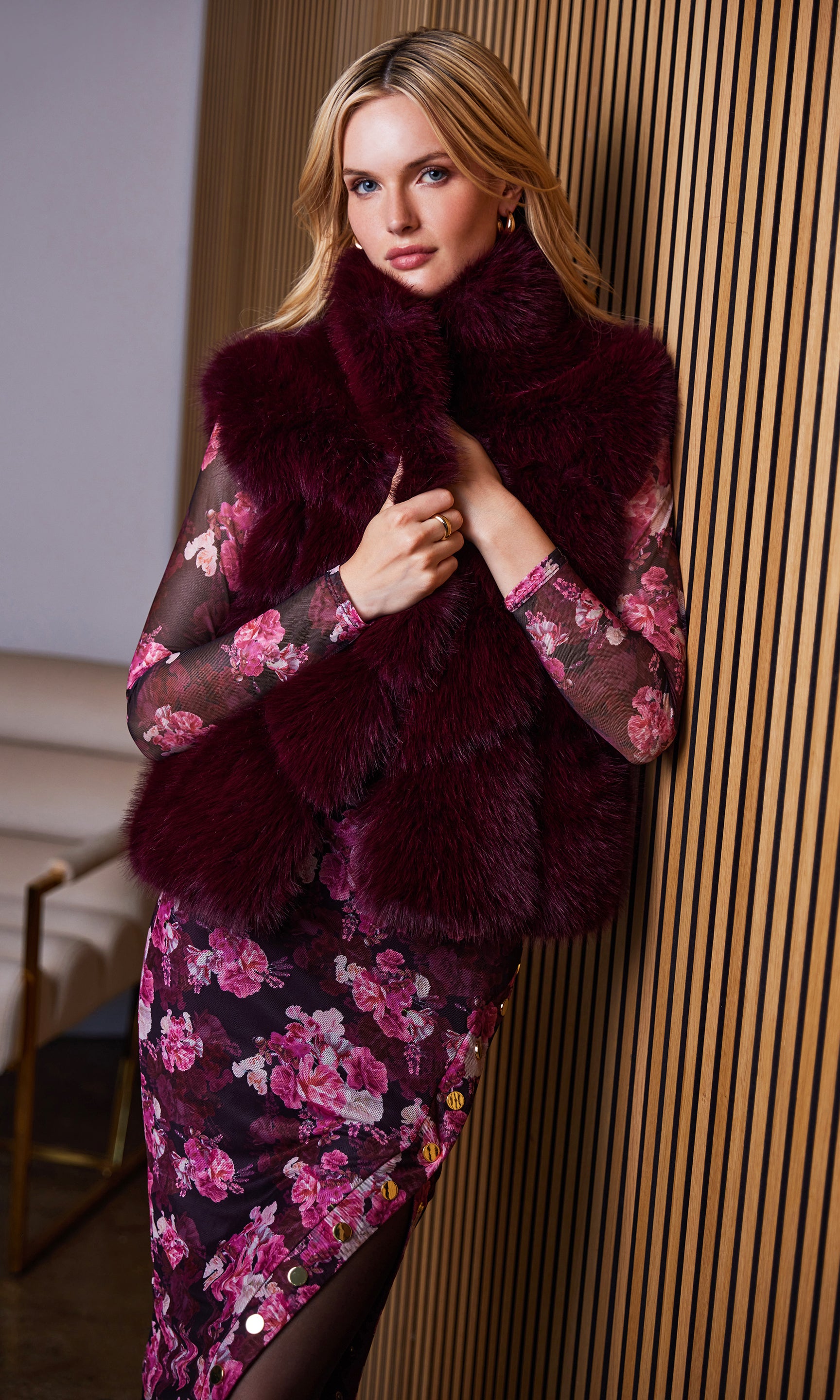 Front view of the model wearing the rosario faux fur vest styled with a floral dress.