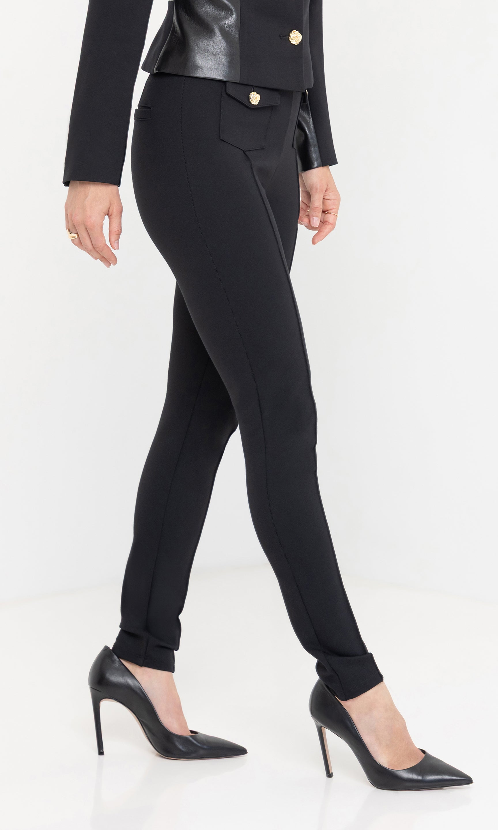 Side view of Roy Ponte Leggings in black, styled with black stiletto heels and a matching black jacket with leather trim, highlighting the sleek, fitted silhouette.