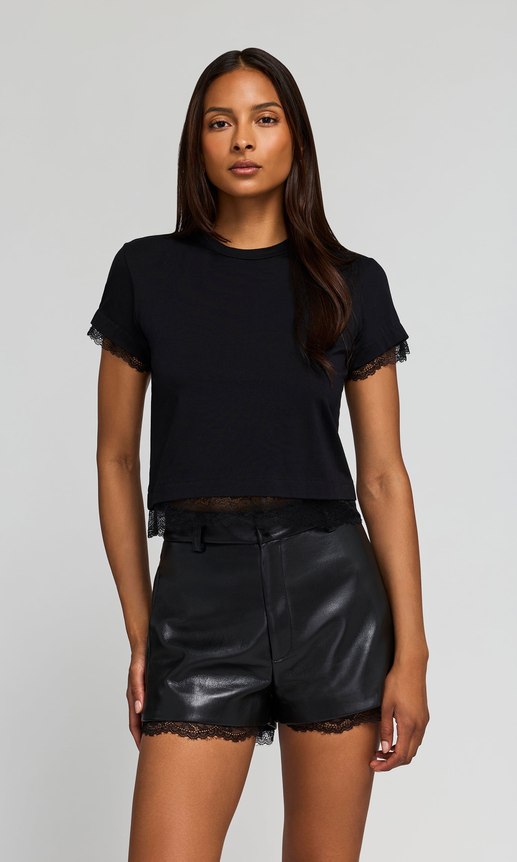 Woman wearing a black top and leather shorts on a white background