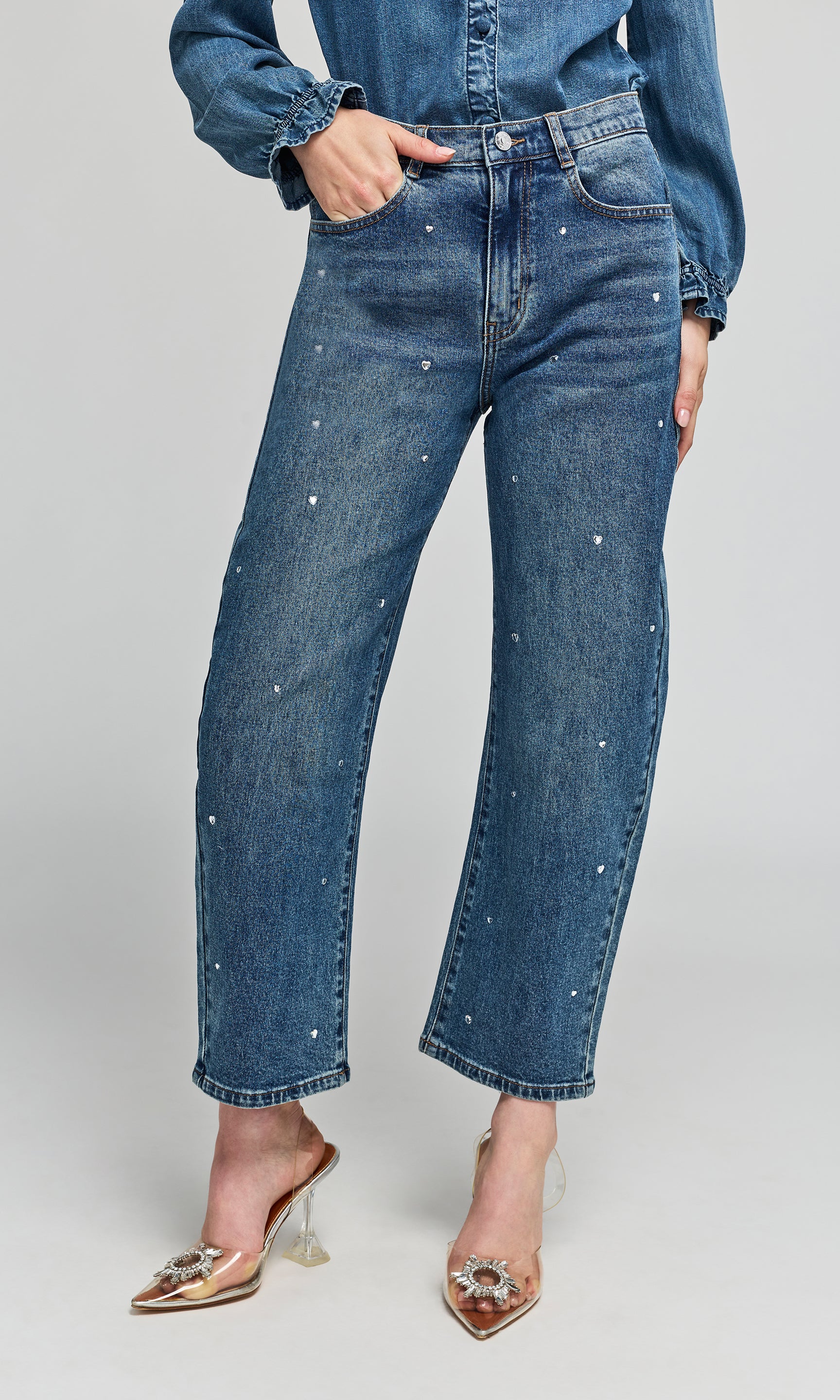 Model wearing blue denim jeans with small heart crystal embellishments down the front, styled with a matching denim shirt.