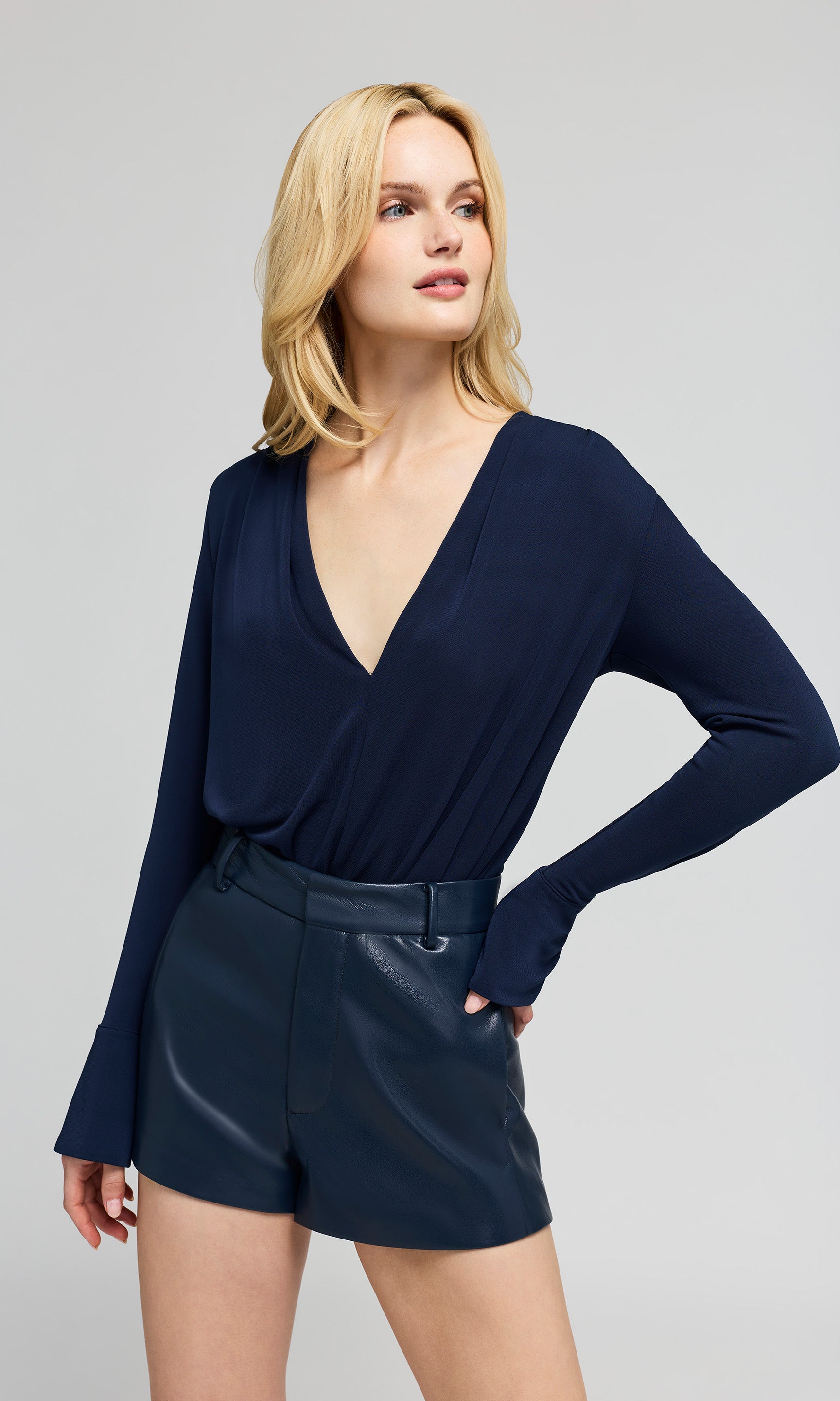 Woman wearing a navy blue long-sleeve top and shorts on a gray background