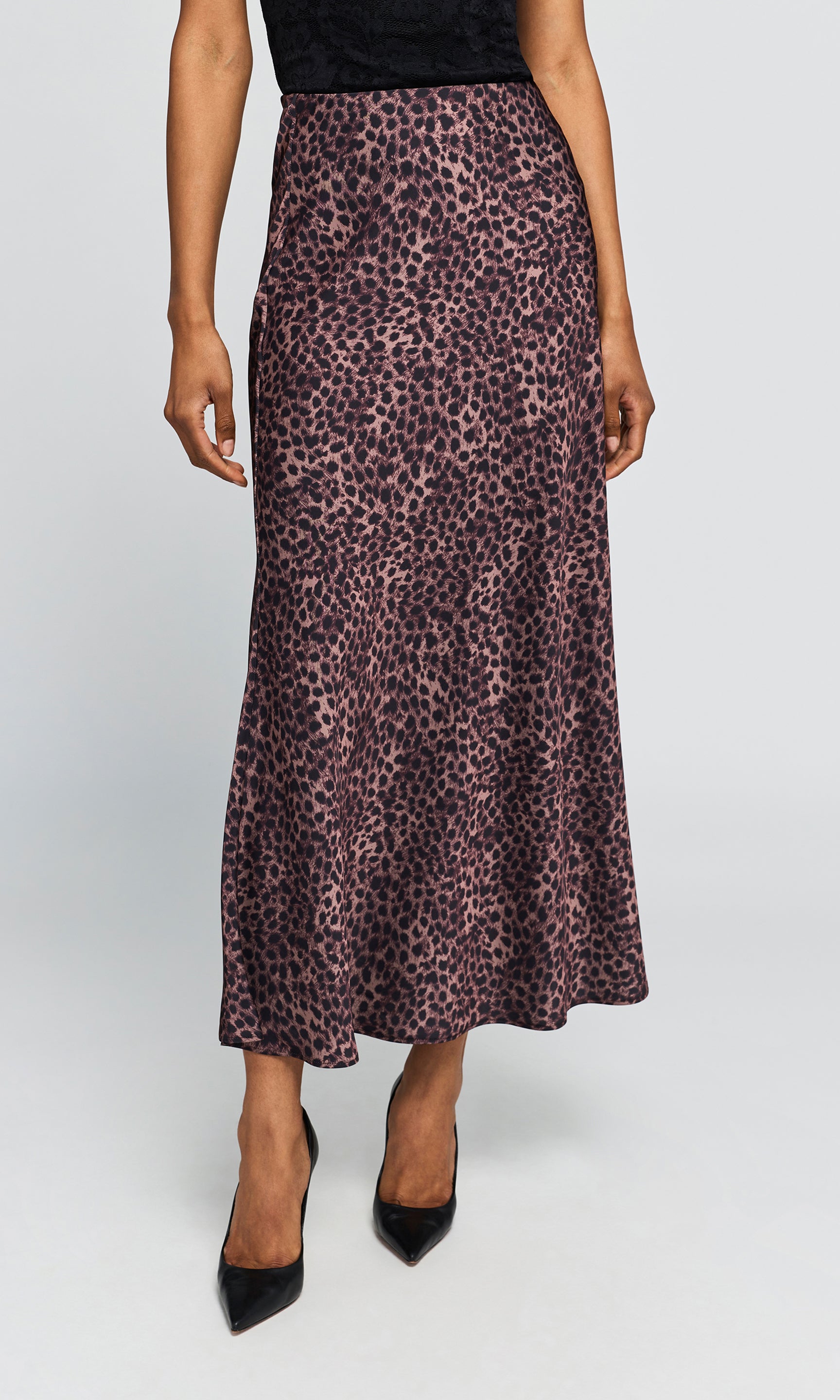 Model wearing a high-waisted, floor-length leopard print skirt, paired with black pointed-toe heels on a plain background.