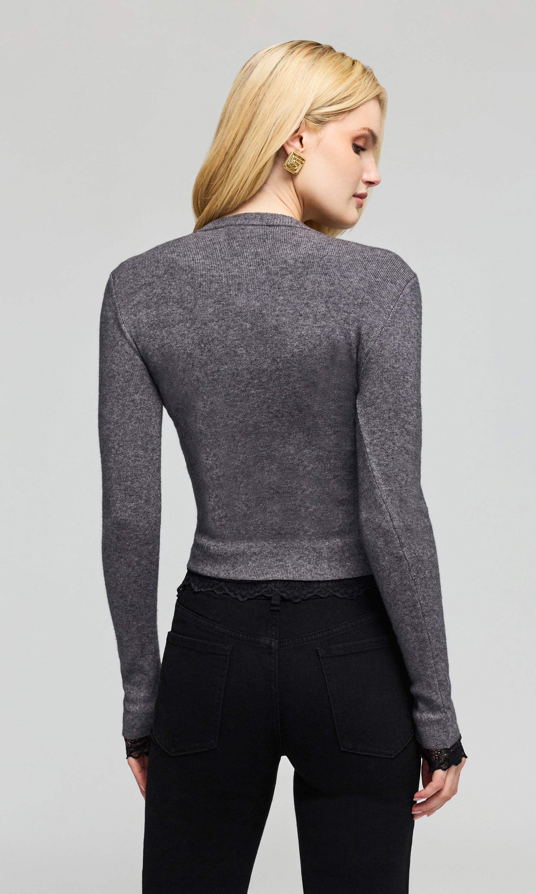 Back view of model wearing a dark gray long-sleeve knit top and black pants on a plain background.