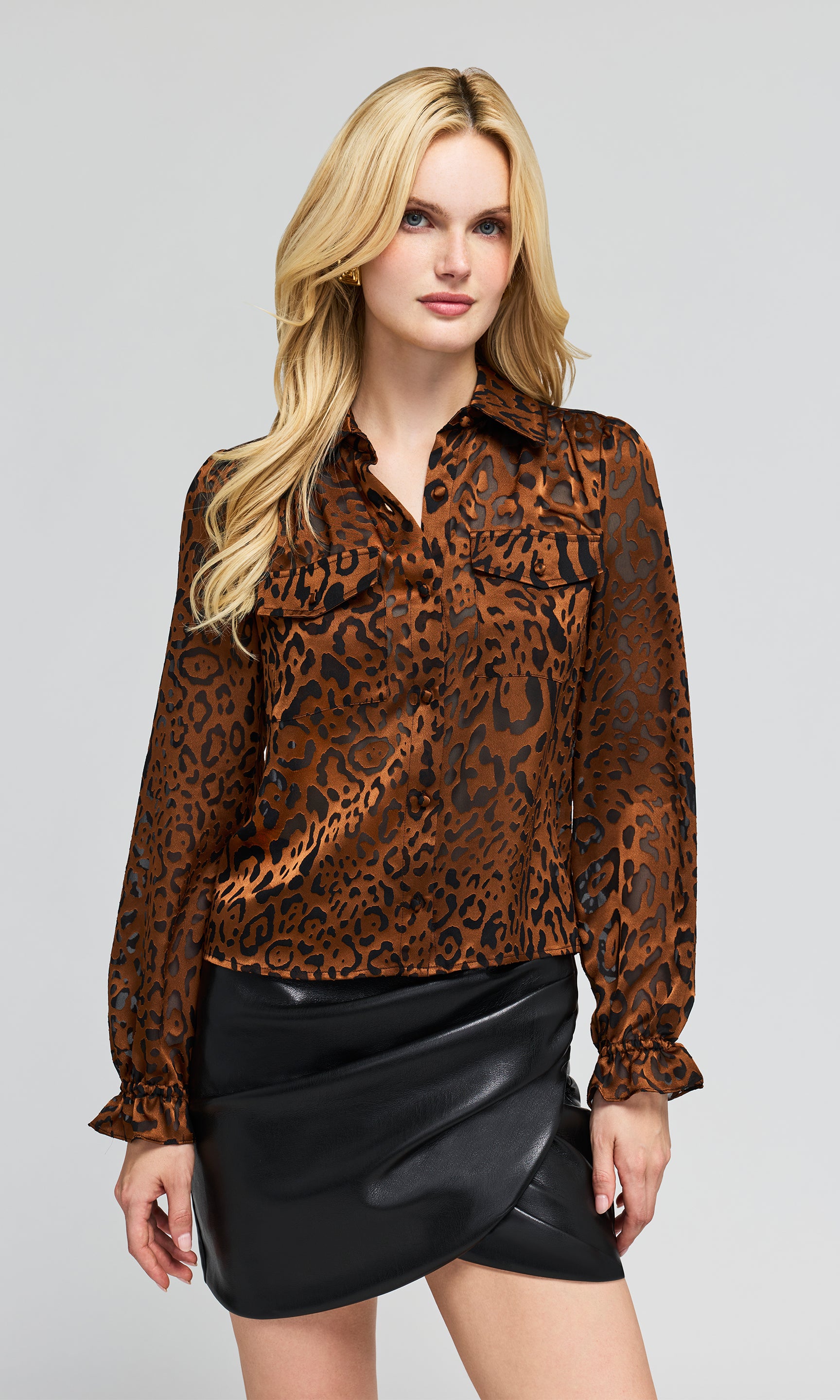 Model wearing a brown and black leopard-print long-sleeve blouse with a black faux-leather wrap mini skirt.
