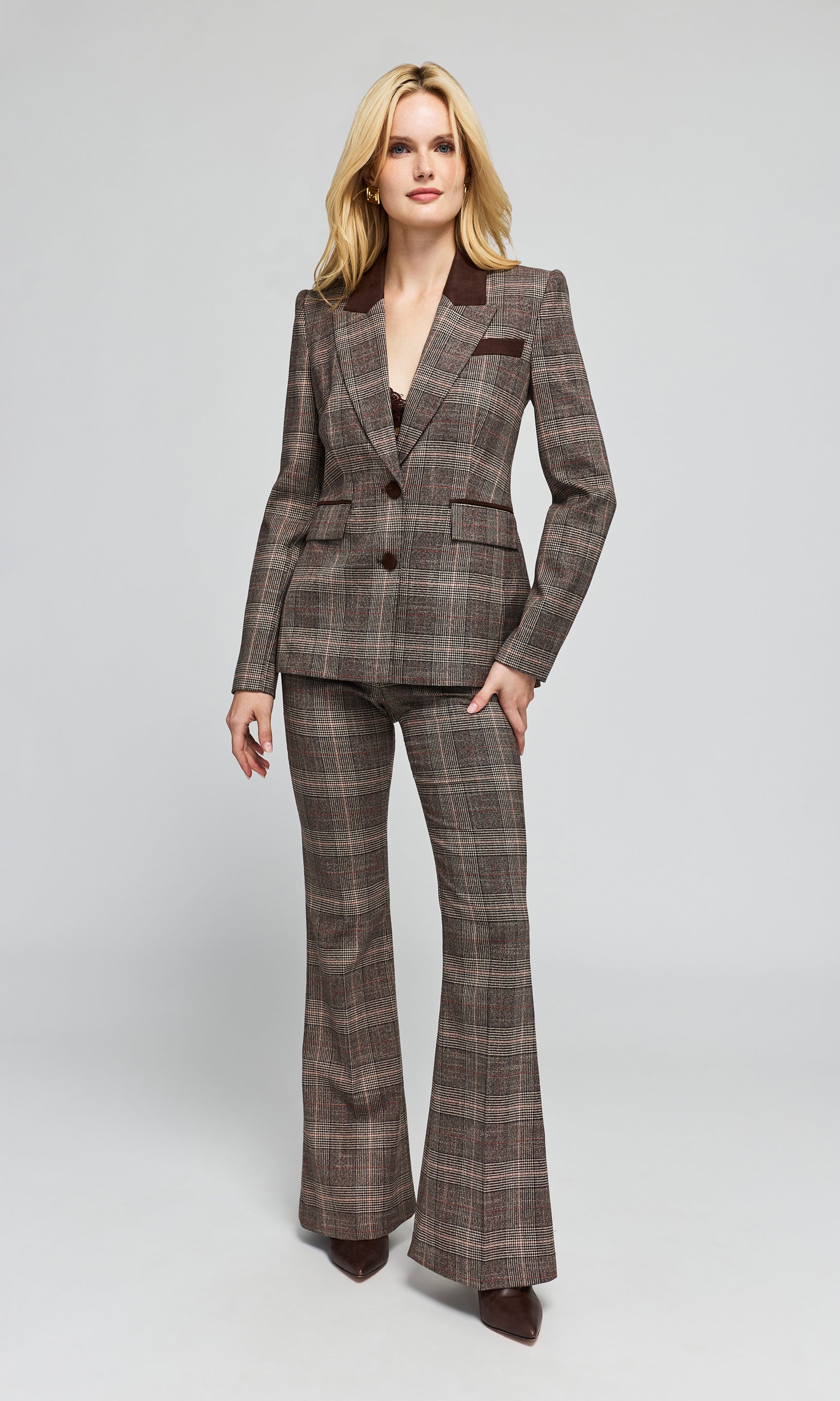 A woman modeling a brown and beige plaid flared pantsuit with dark brown lapels.