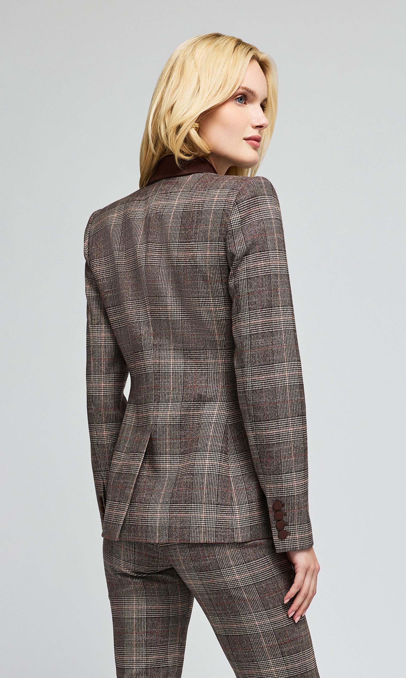 Back view of model wearing a brown and gray plaid blazer with dark brown lapels, styled over a brown lace camisole and matching plaid trousers.