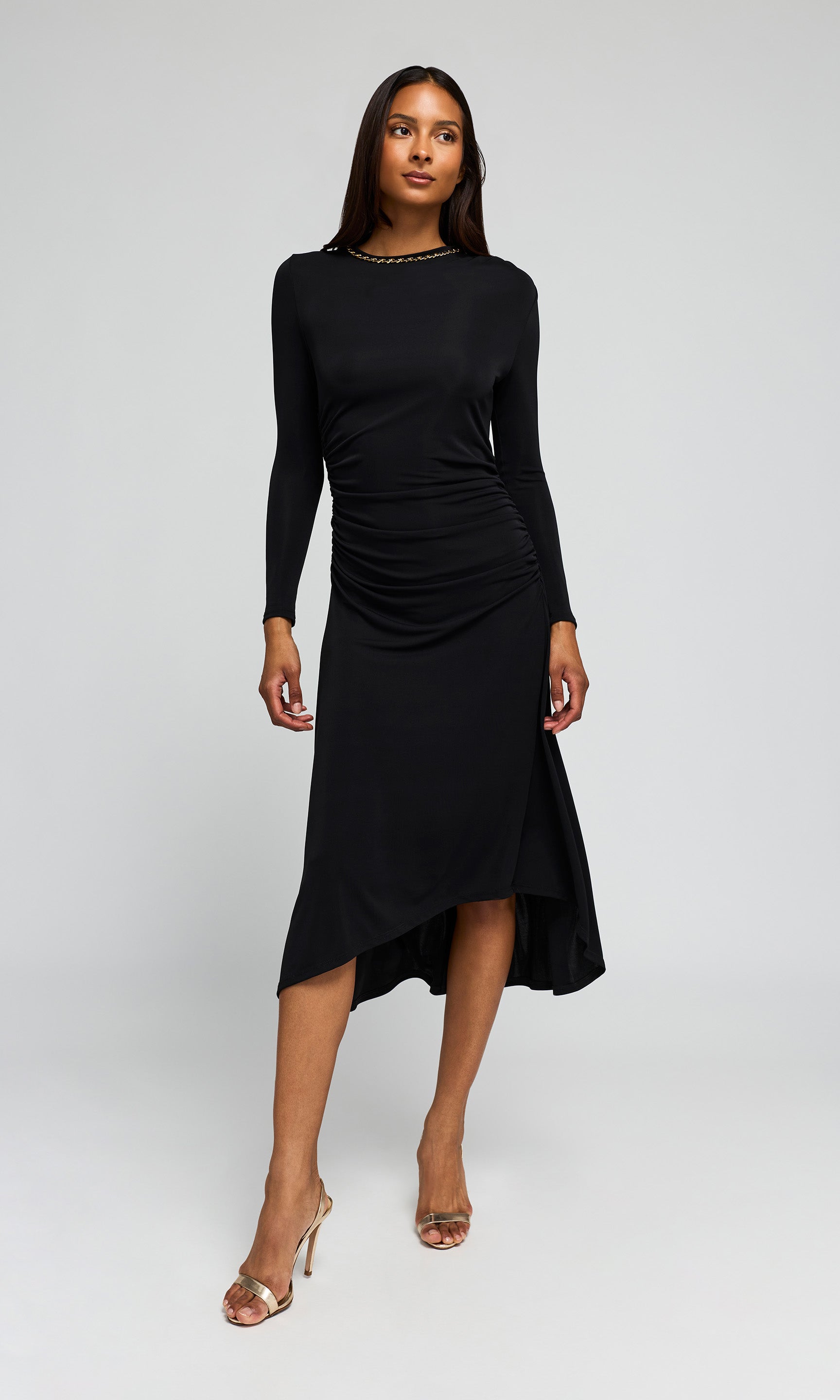 Model wearing a black long-sleeve midi dress with a gathered, ruched bodice on a background.