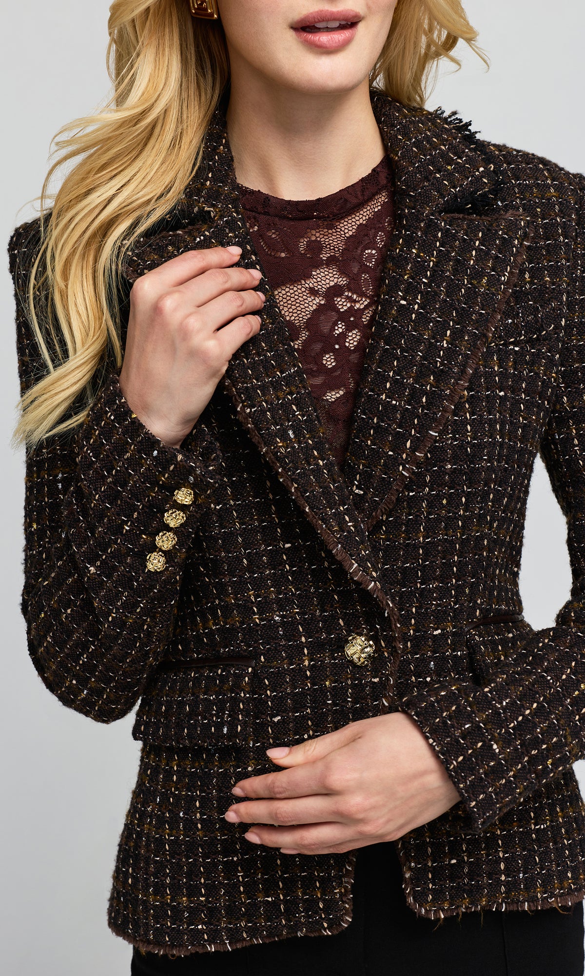 Close-up of a double breasted brown tweed blazer with gold button details over a burgundy top.