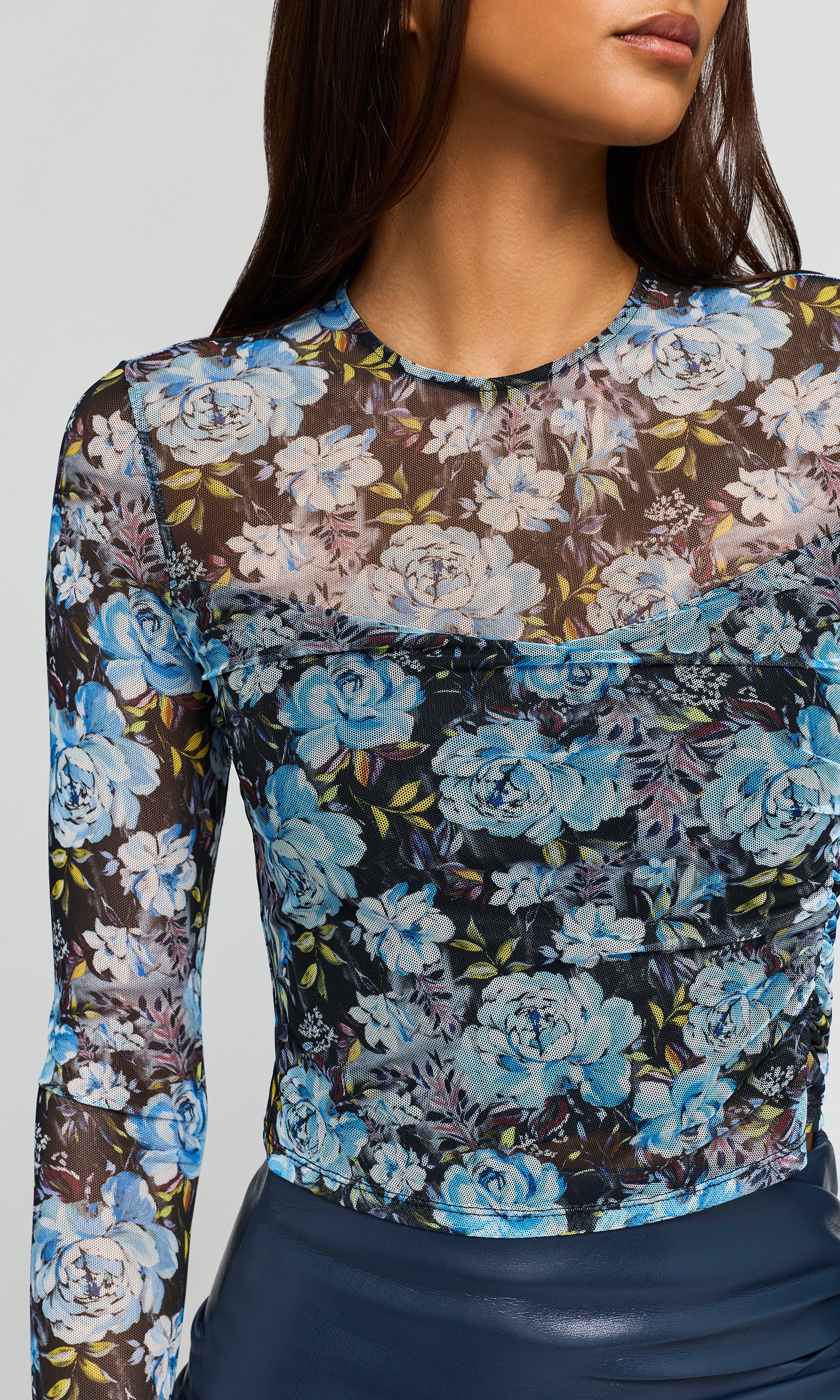 Close-up of model wearing a blue floral mesh crop top on a plain background.