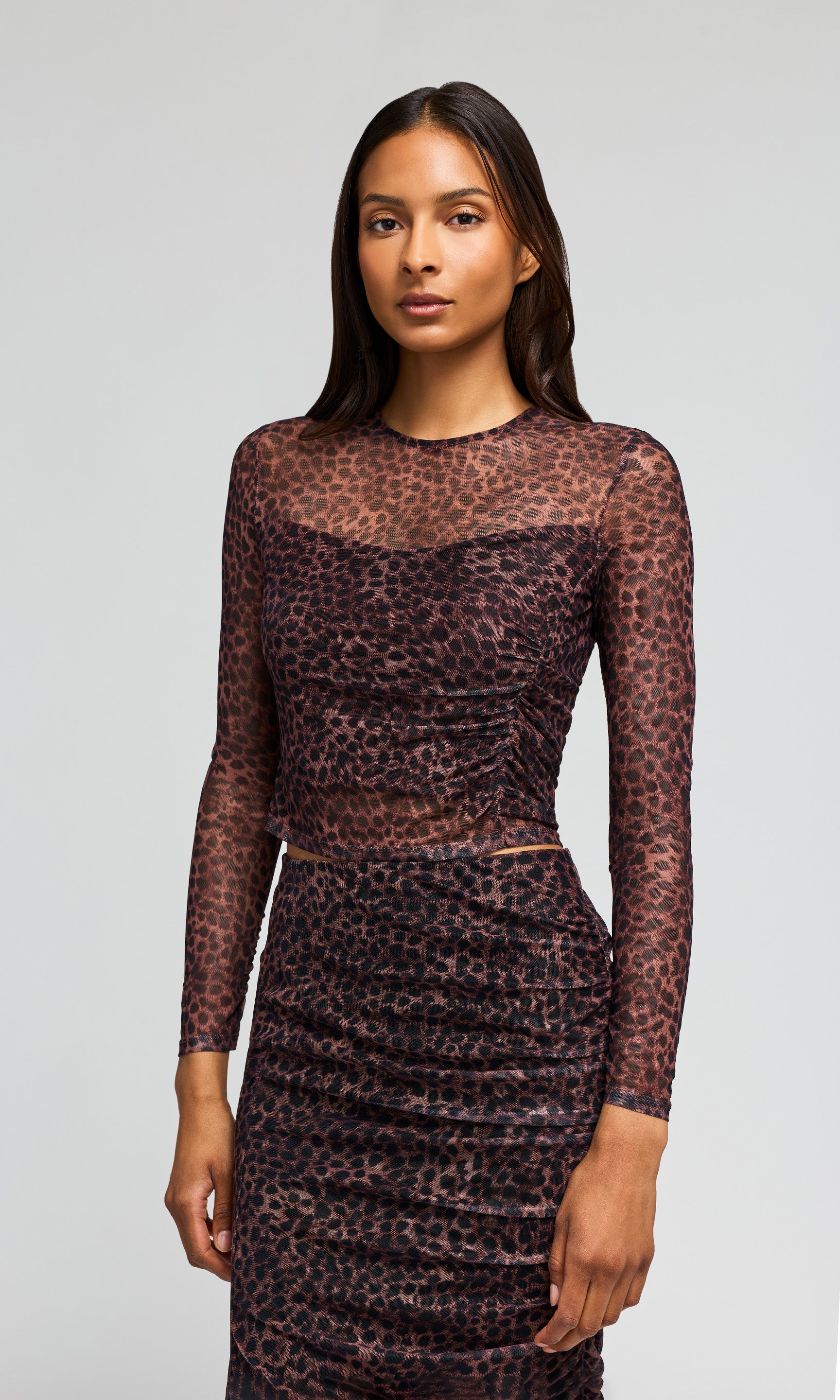 Side view of model wearing a sheer leopard-print mesh two-piece on a plain background.