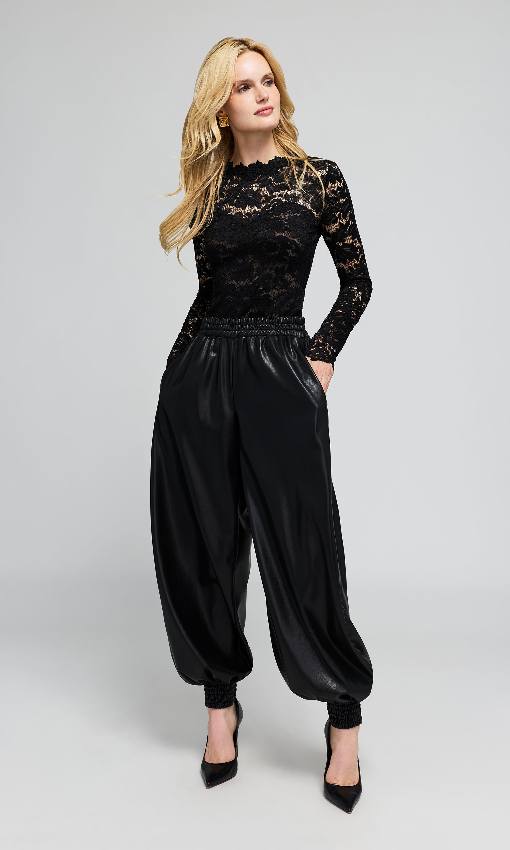 A woman modeling a black long-sleeve lace top, paired with gathered balloon-style black pants.