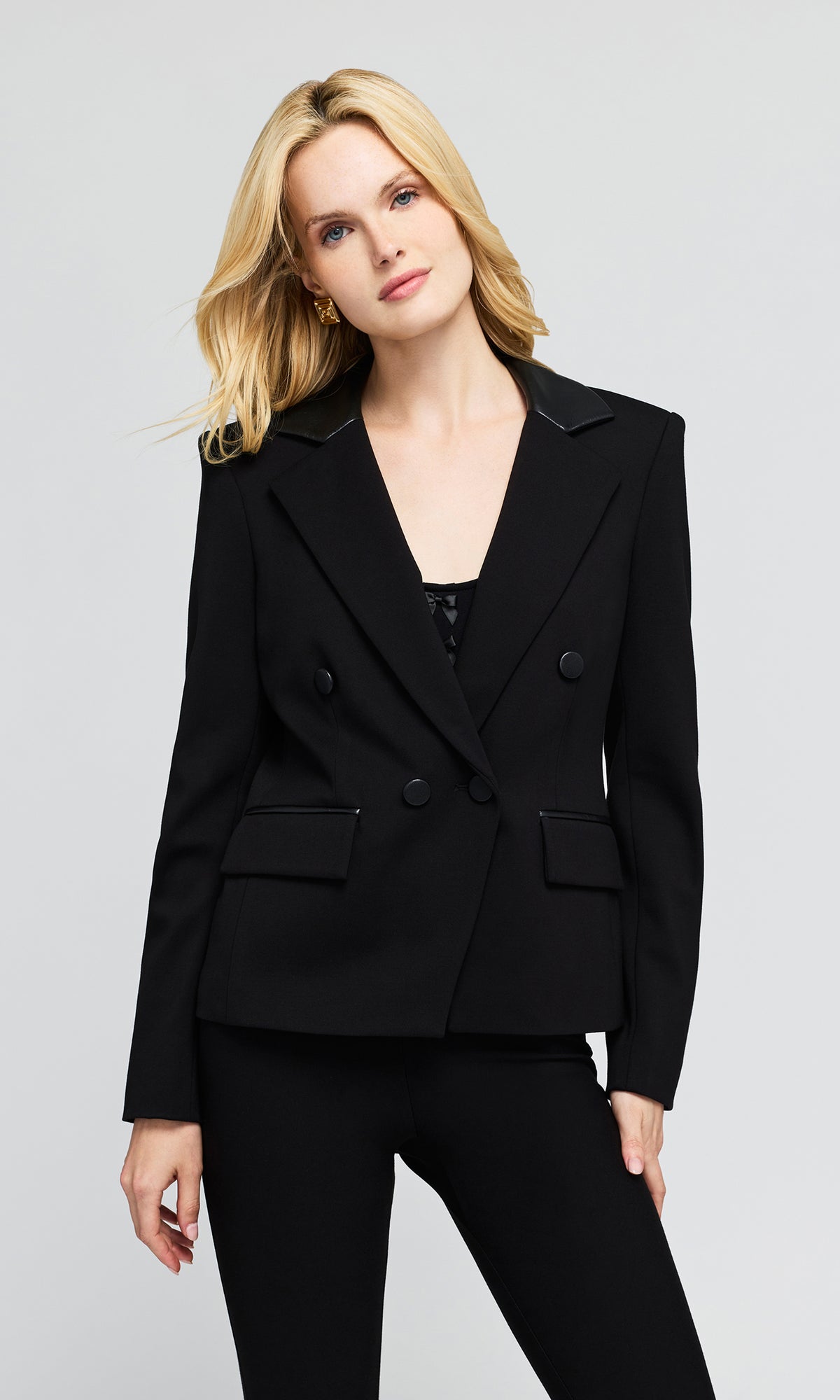 Model wearing a black double-breasted blazer with structured shoulders and black pants.