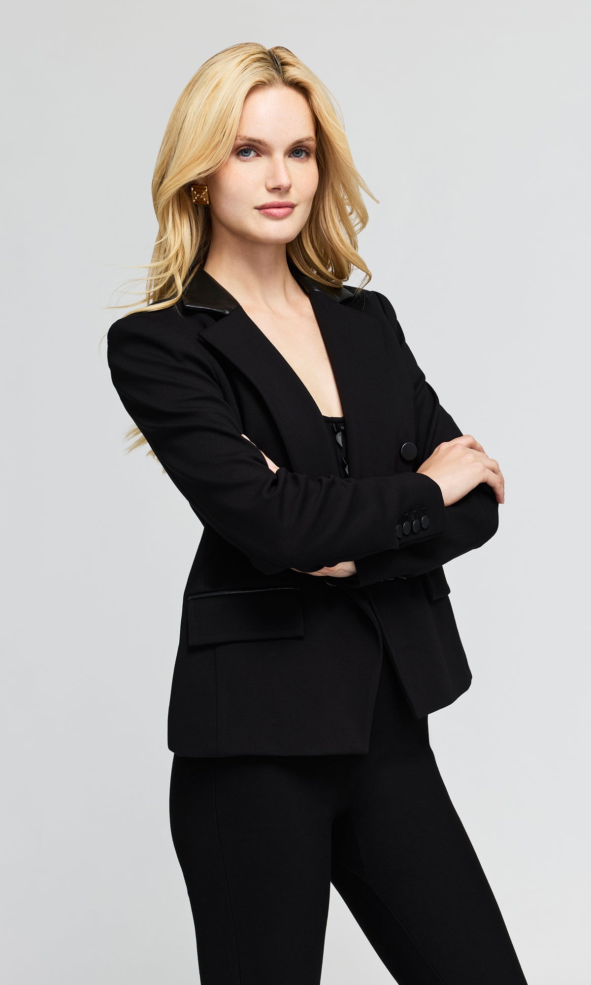 Side view of model wearing a black double-breasted blazer with structured shoulders and black pants.