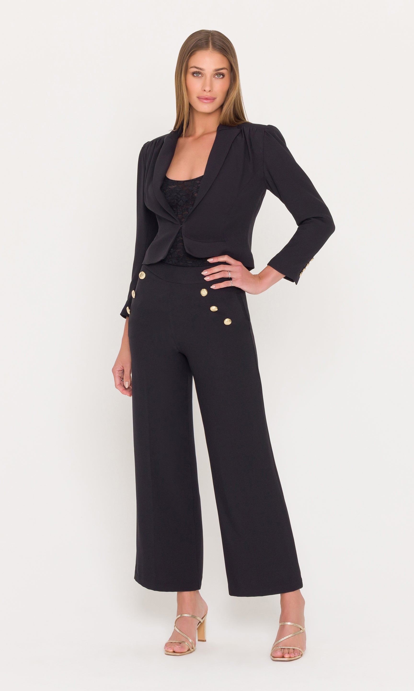 Full body image of woman wearing a black outfit with gold buttons on a white background