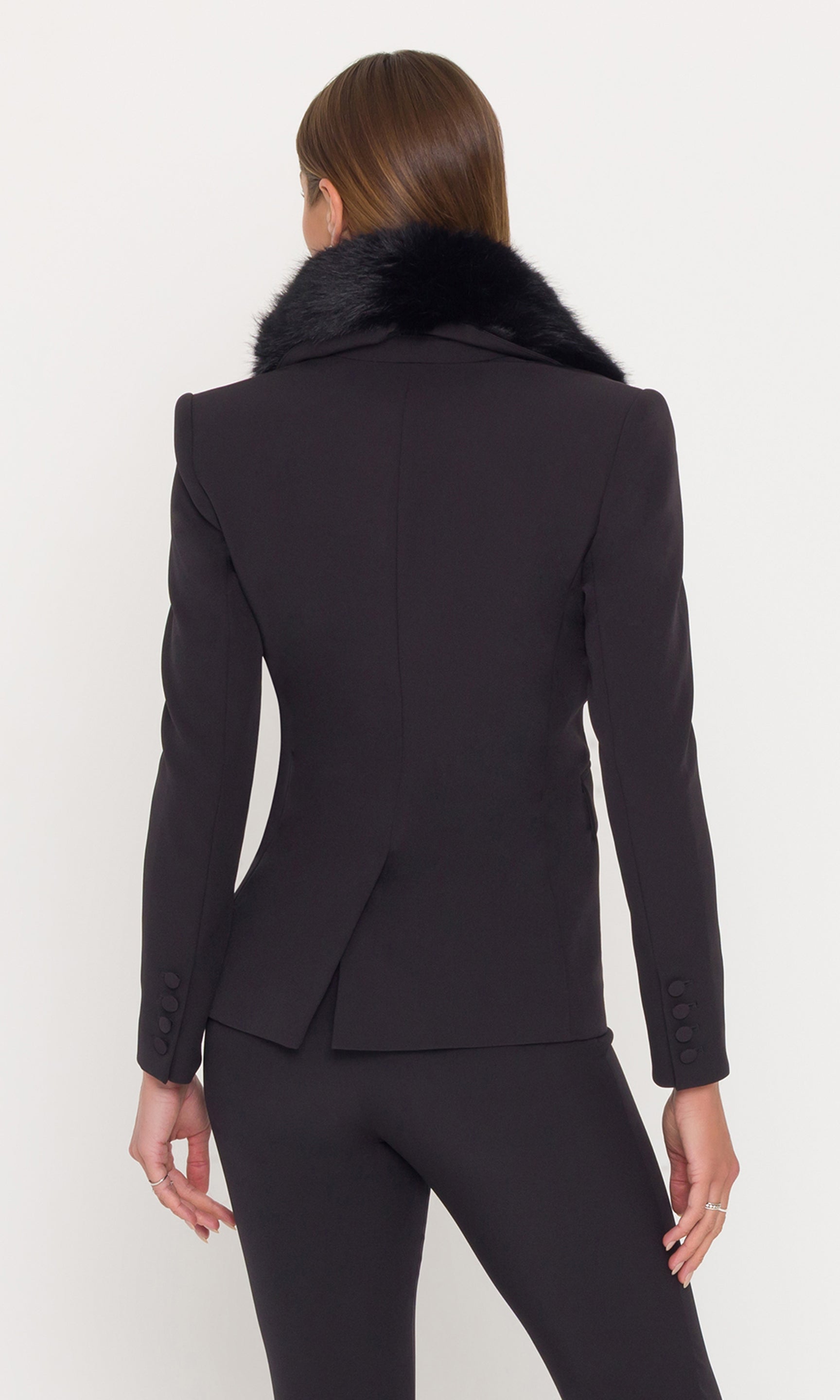 Back view of model wearing a black crepe blazer with a fur collar and black pants