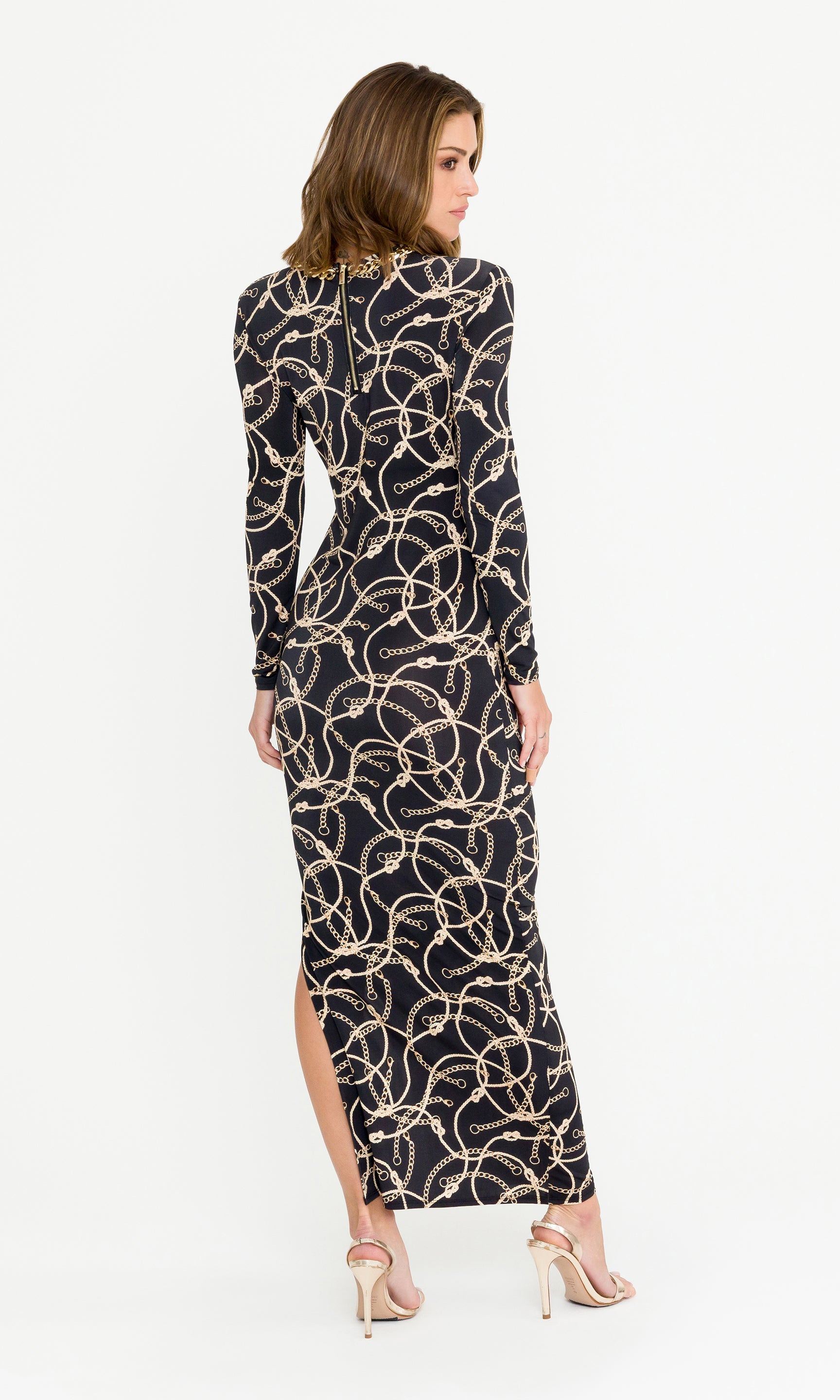 Back view image of model wearing a long black dress with gold pattern on a white background