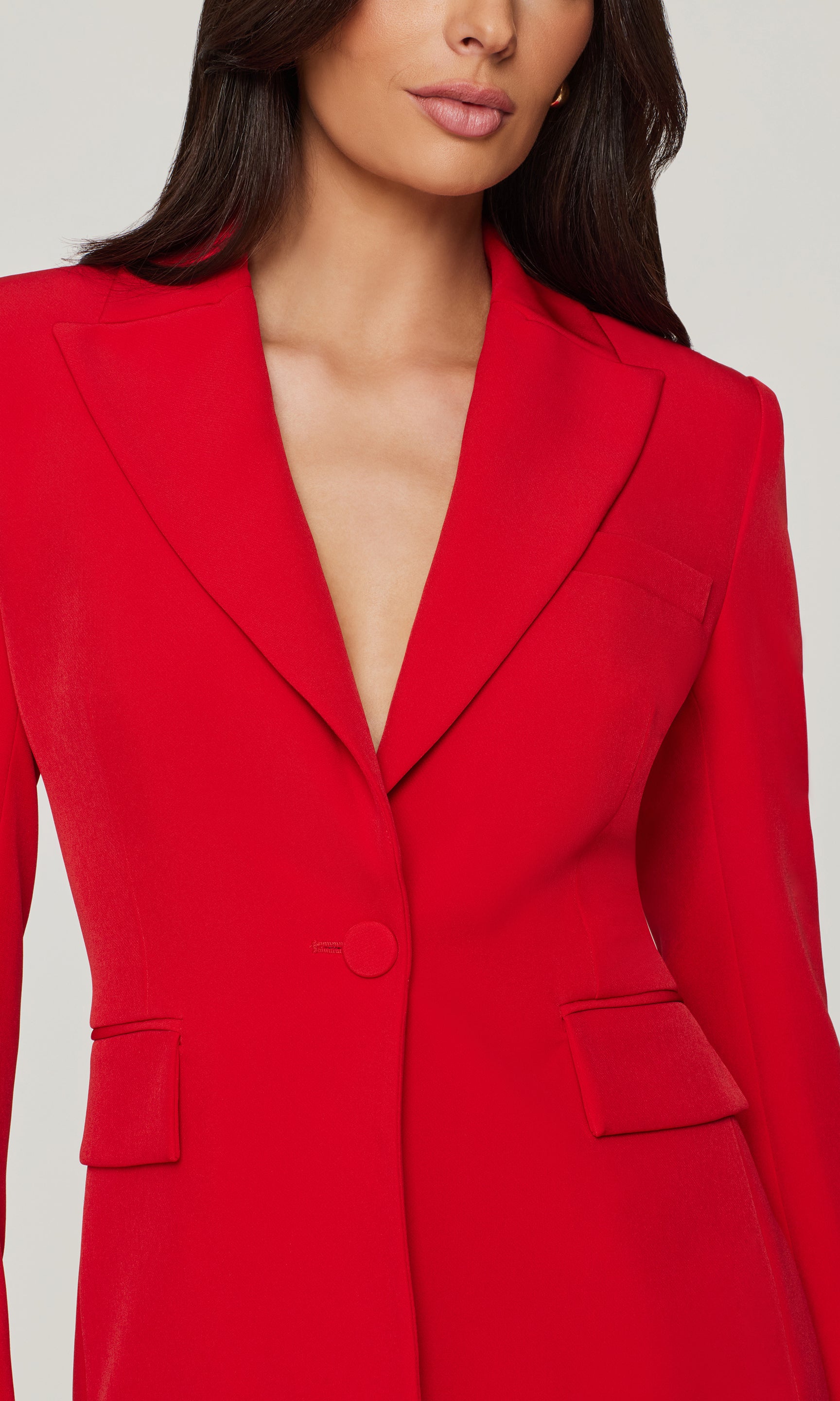 Close-up of red blazer worn by a model on a plain background