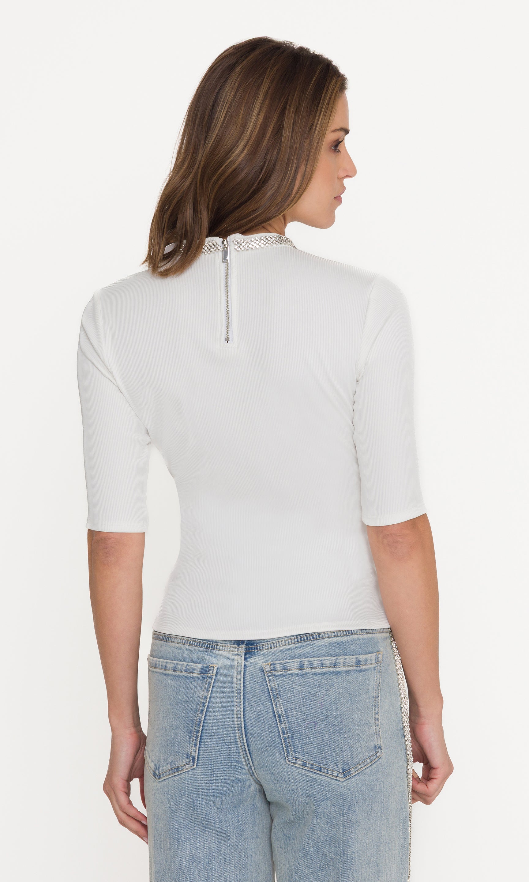 Woman wearing a white short-sleeve top and light blue jeans on a white background