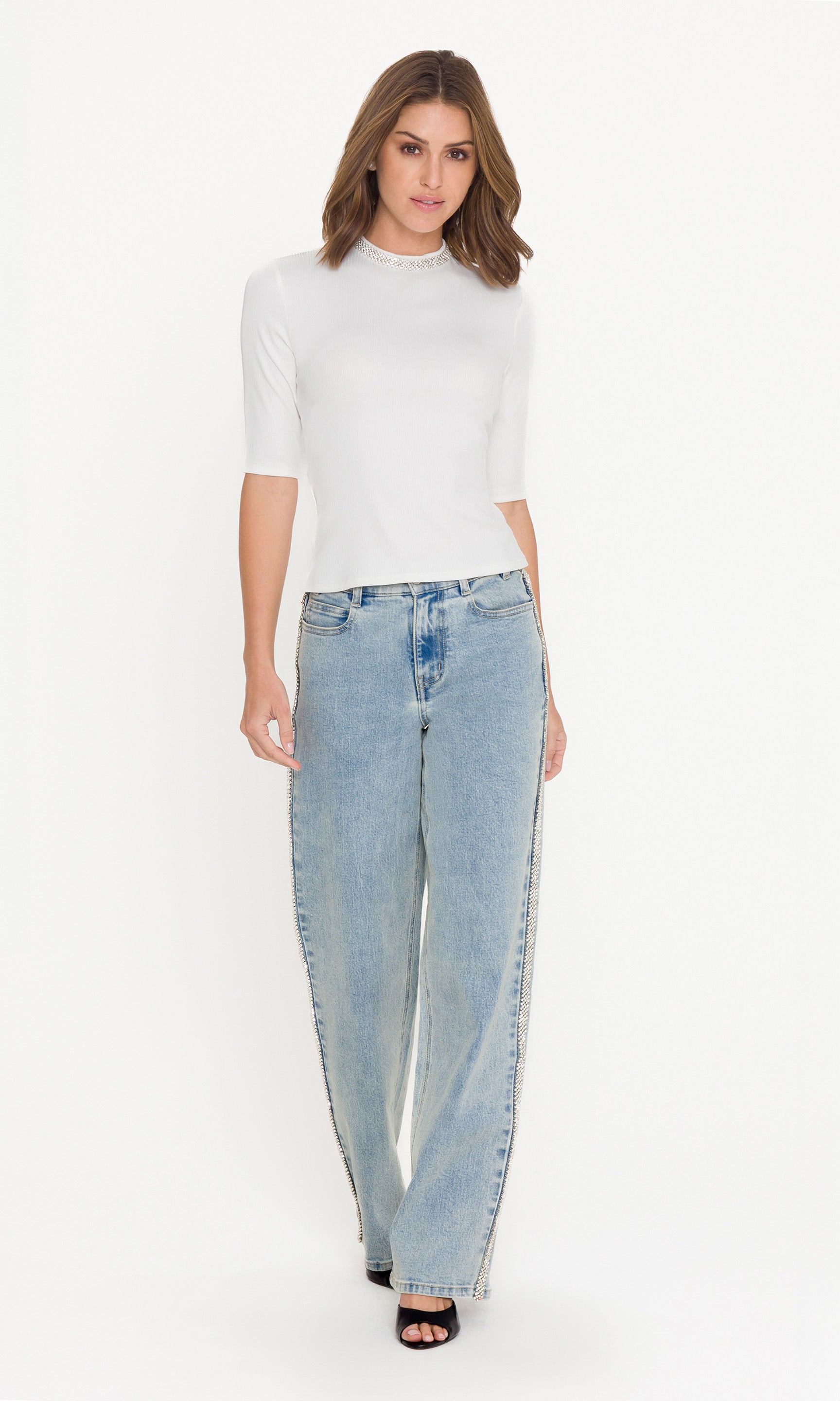 Woman wearing a white top and light blue jeans on a white background