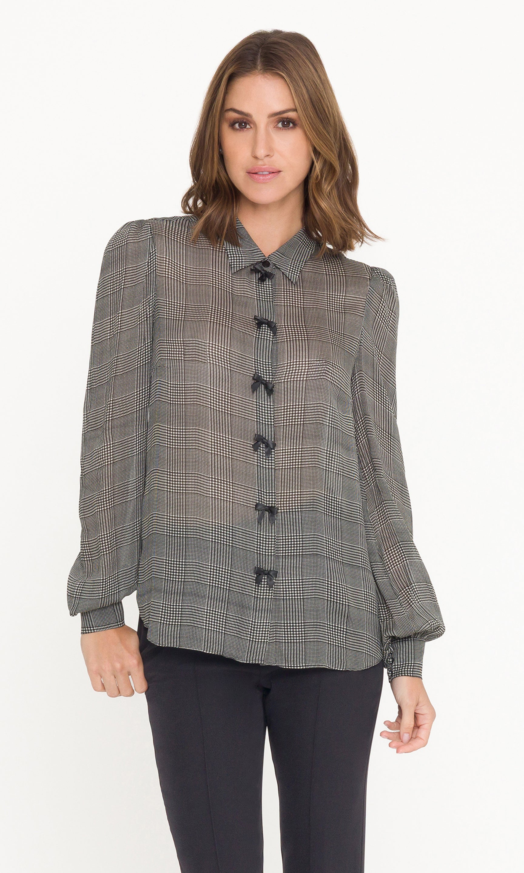 Woman wearing a gray checkered blouse with black bows on a white background