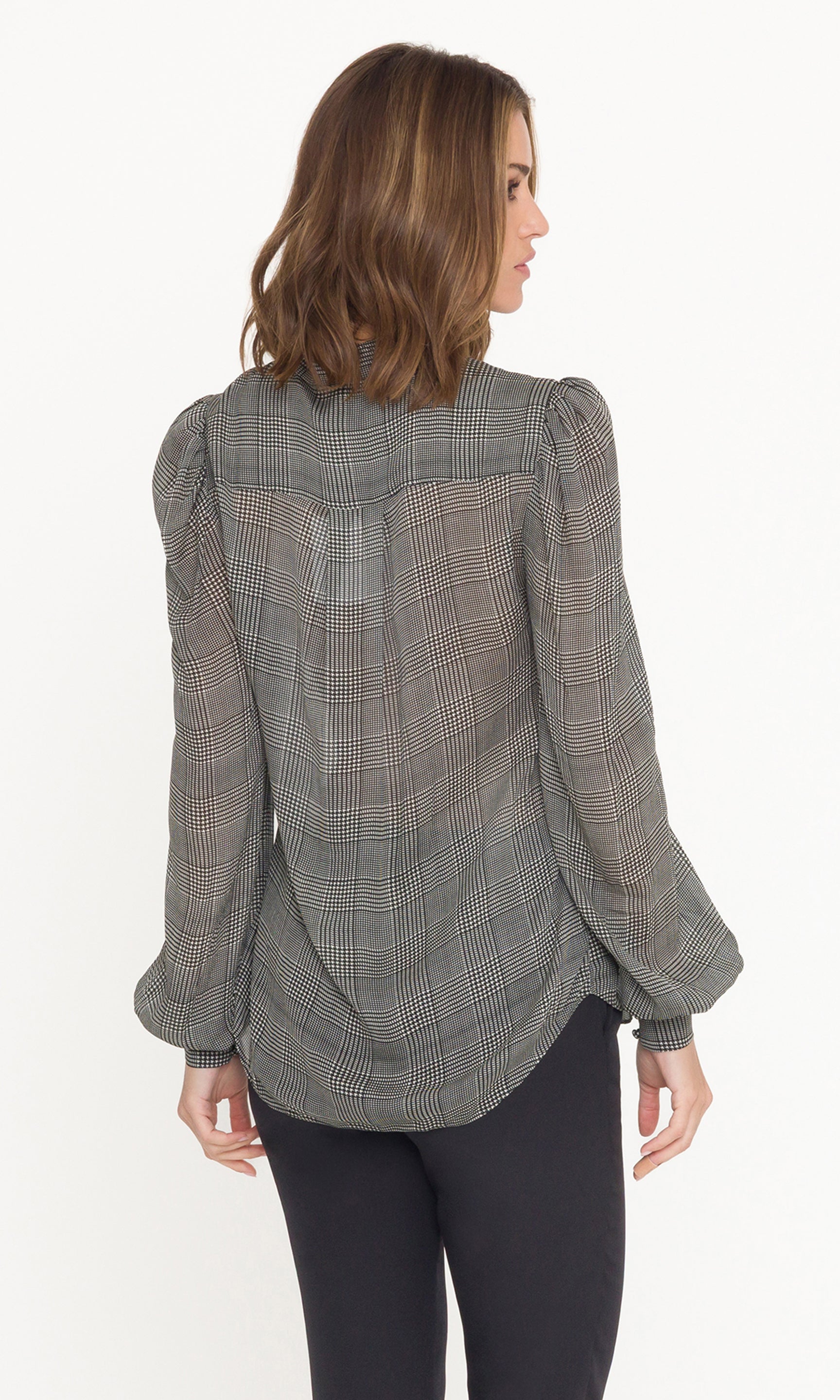 Woman wearing a gray checkered blouse with puffed sleeves on a white background