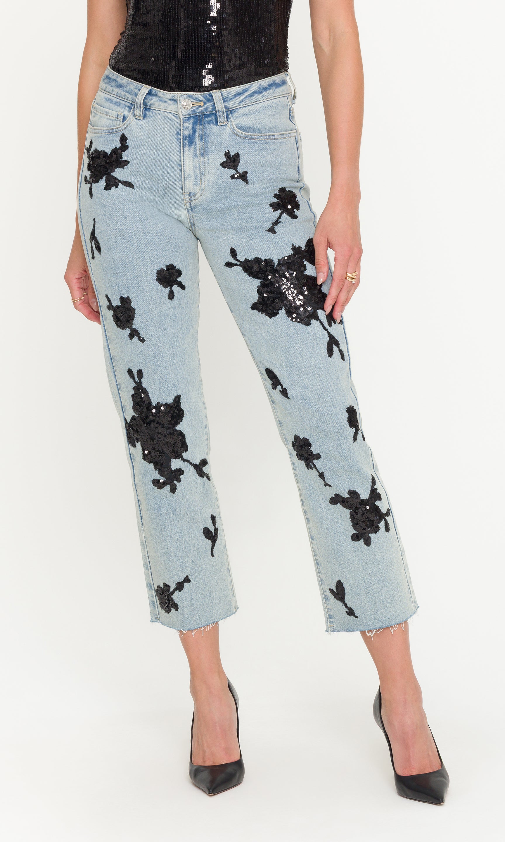 Light blue jeans with black floral sequin patterns worn by a person on a white background