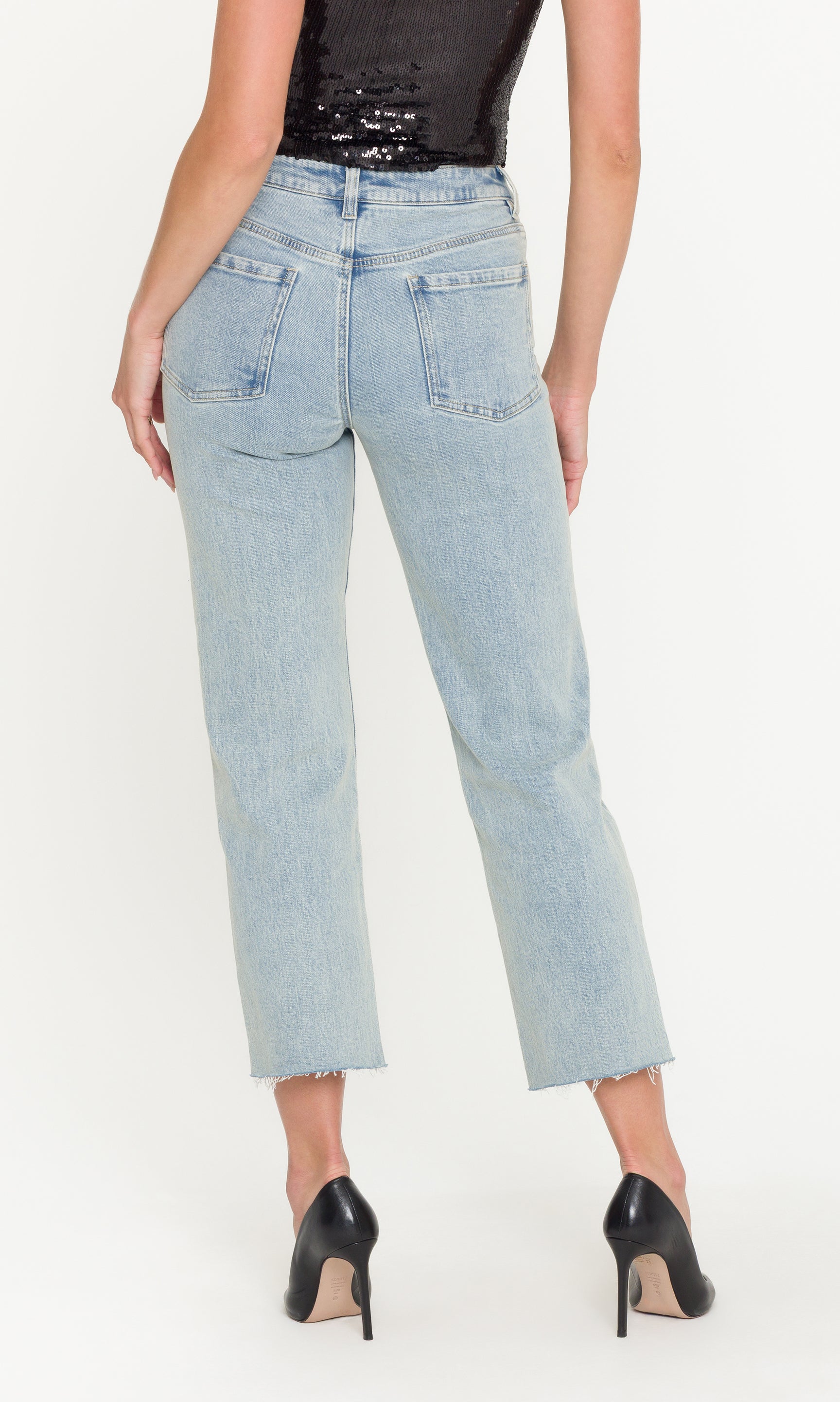 Back view of light blue jeans worn by a person on a white background