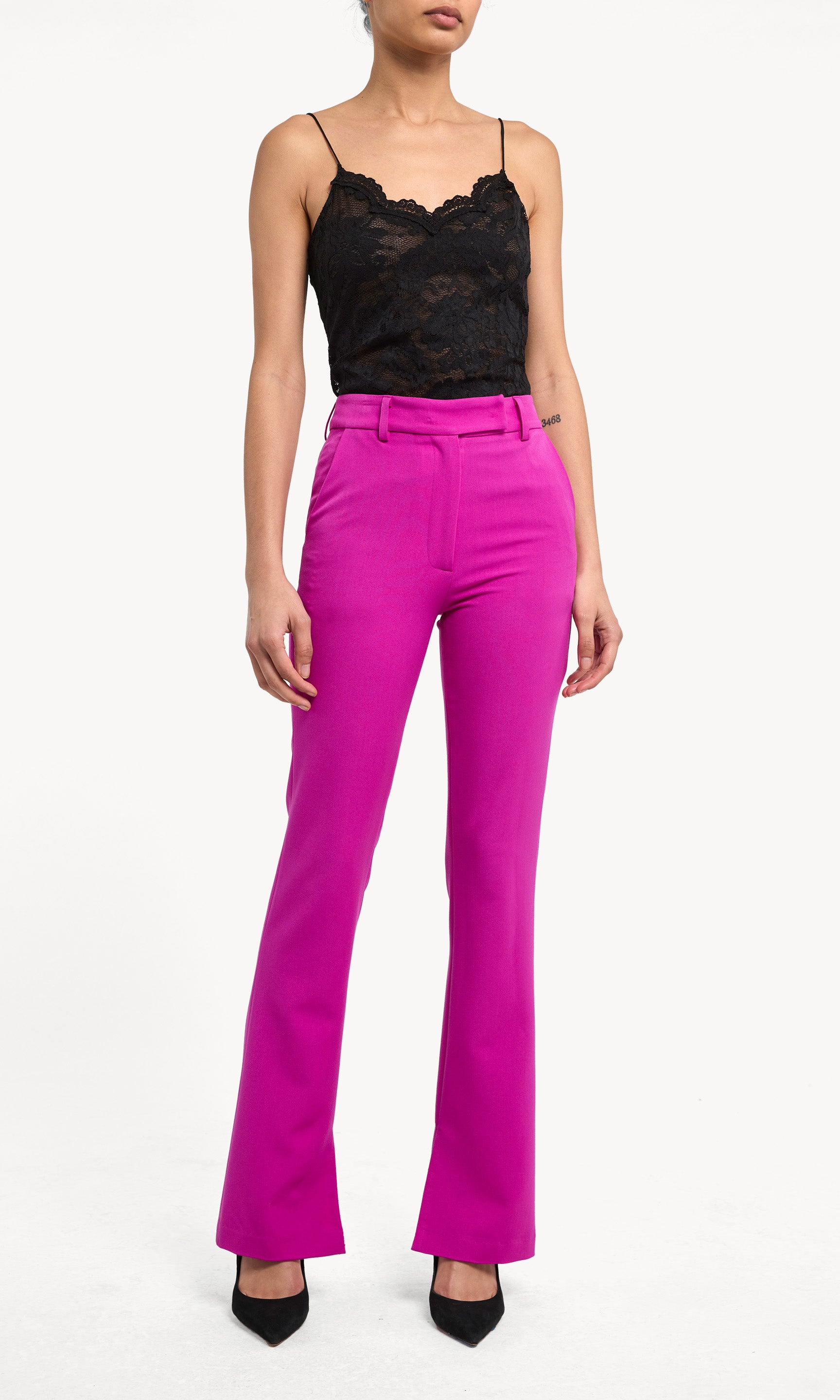 Person wearing a black lace top and bright pink pants on a white background