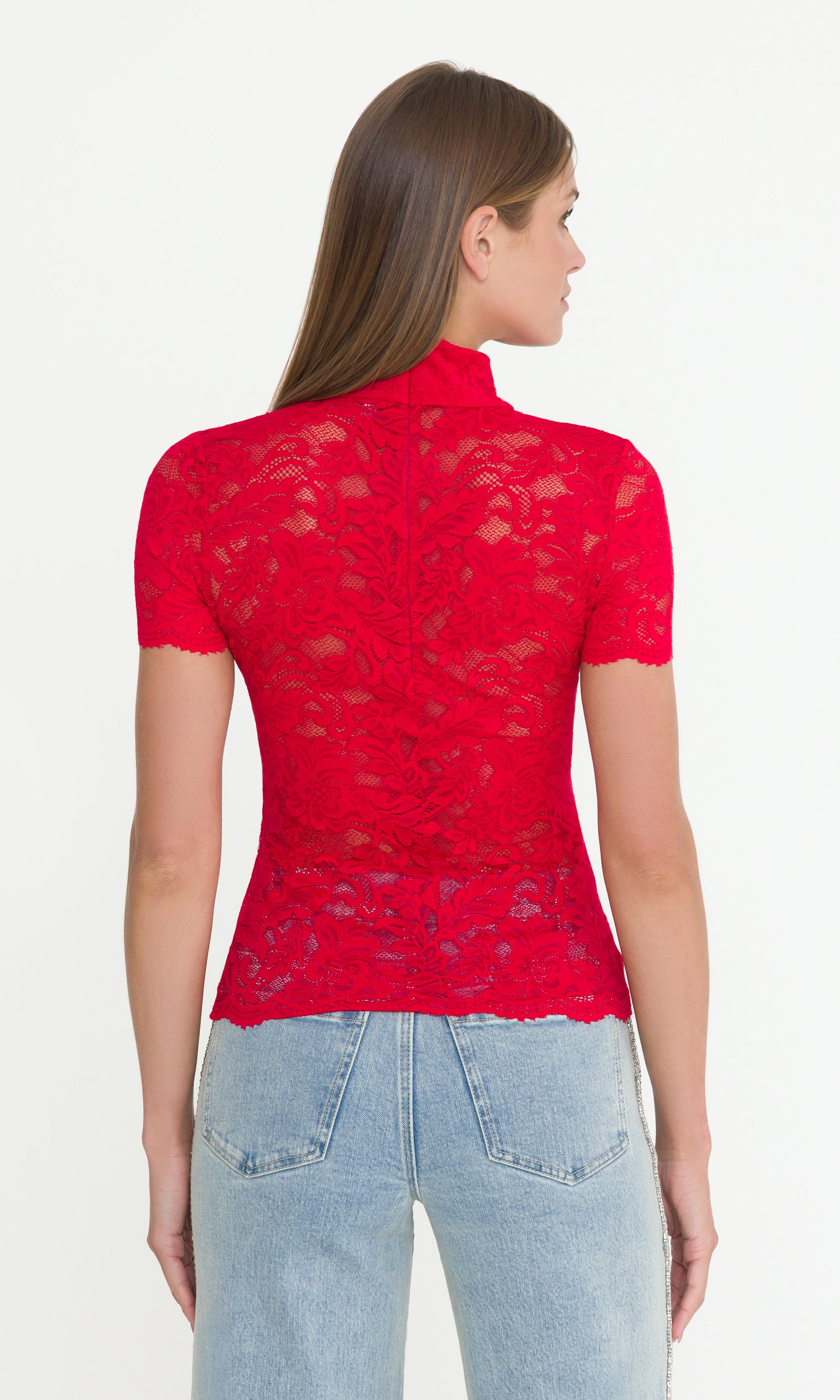 Back view of woman wearing a red lace top and light blue jeans on a white background