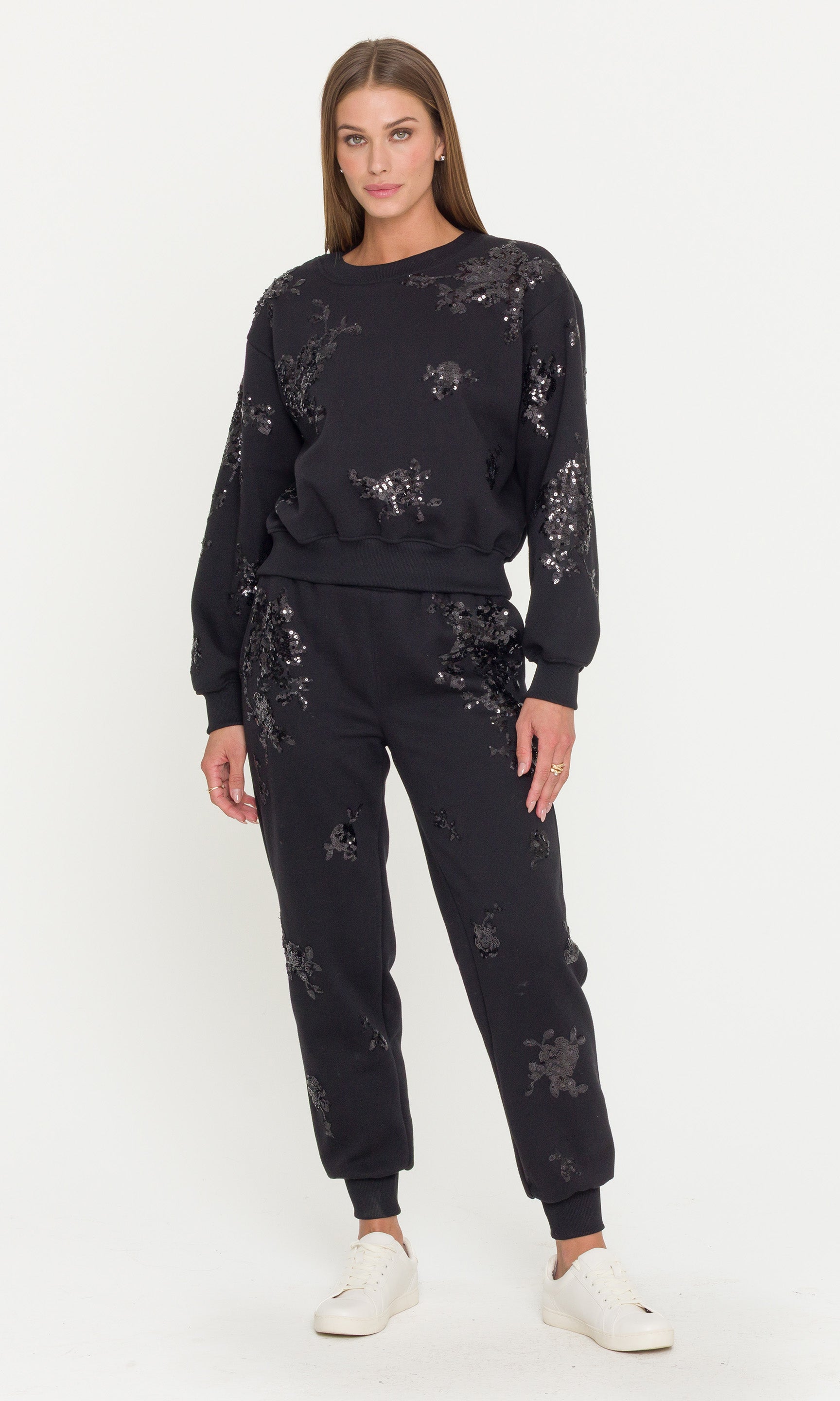 Woman wearing a black sequin sweatsuit outfit on a white background