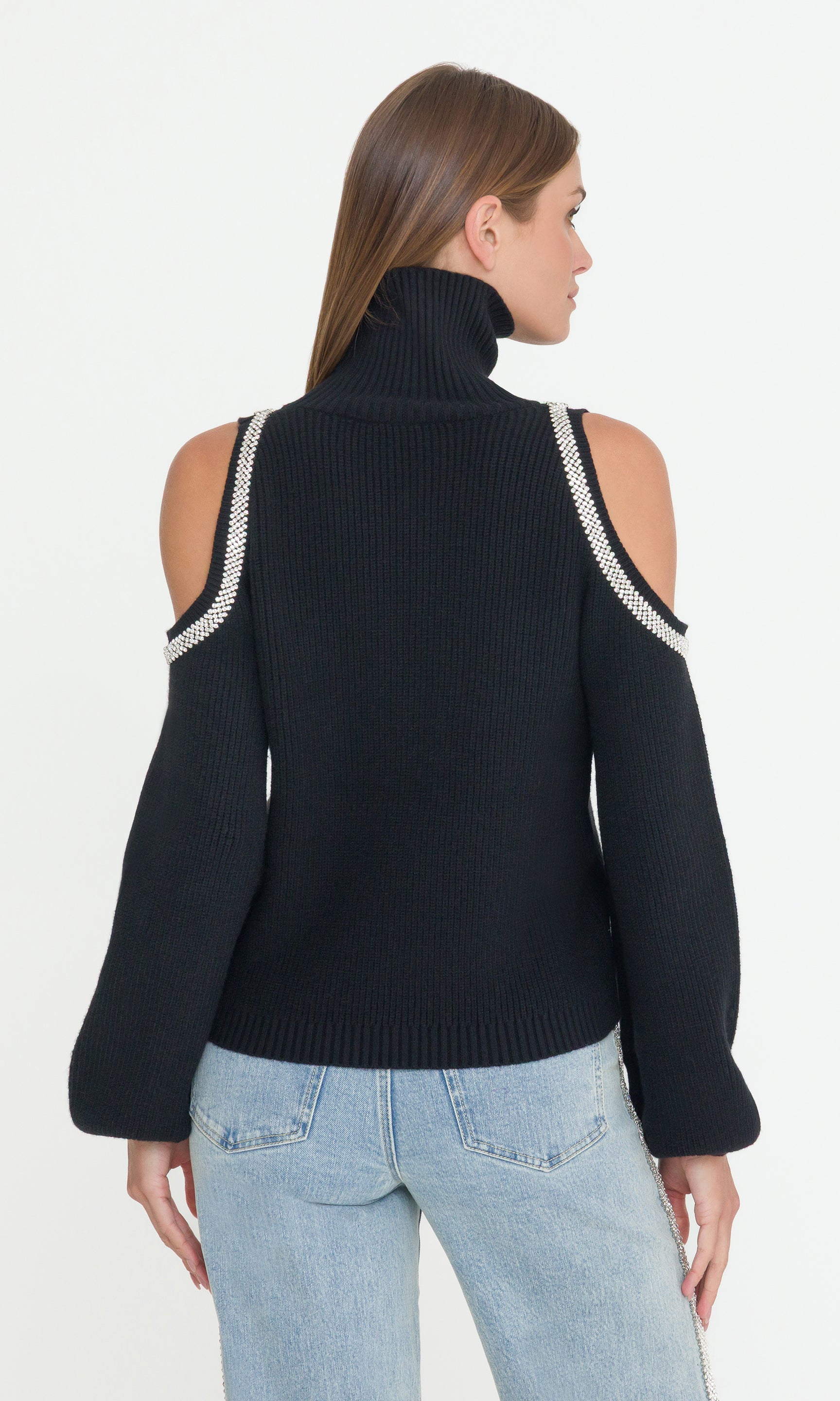 Woman wearing a black sweater with crystal trims on the cold-shoulders on a white background