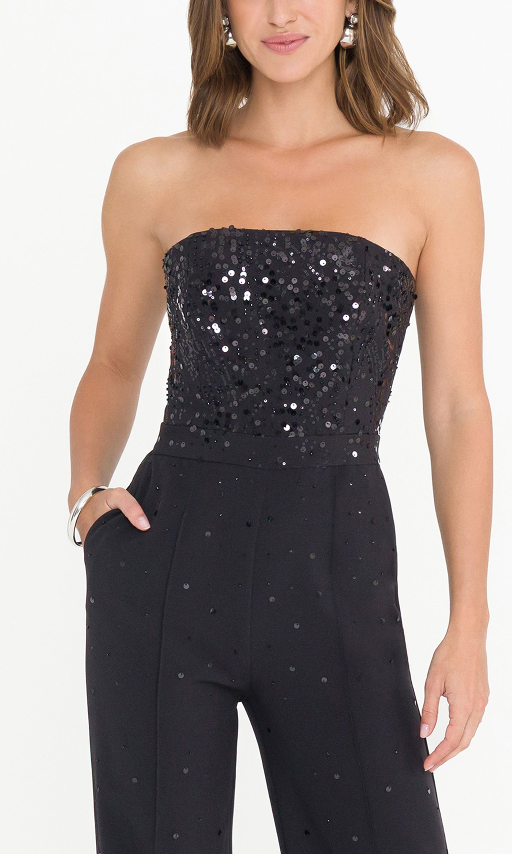 Detail image of black strapless sequin jumpsuit worn by a model, showcasing the scatter sequin embellishment details.