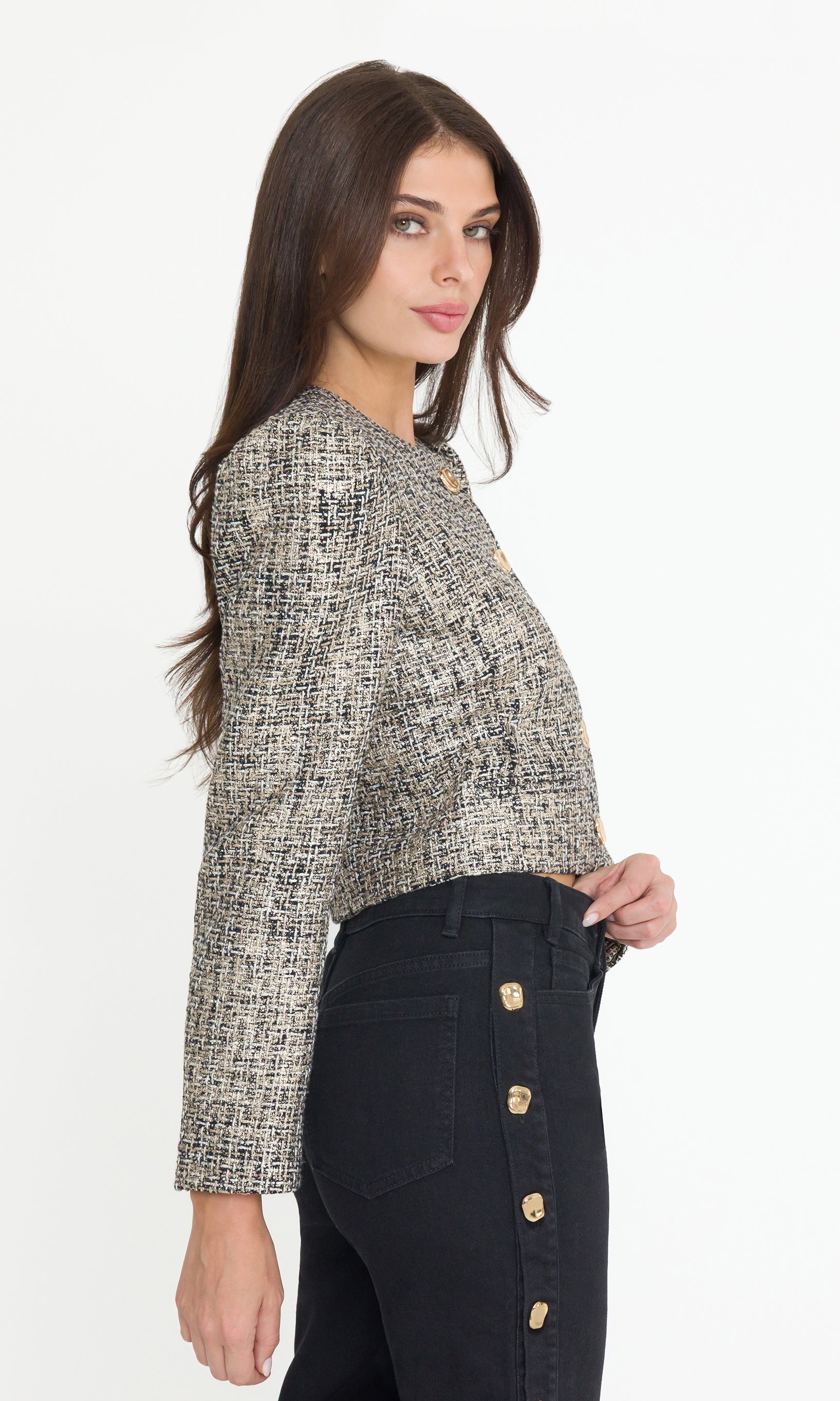 Side view of Woman wearing a gold multi tweed jacket with black jeans on a white background