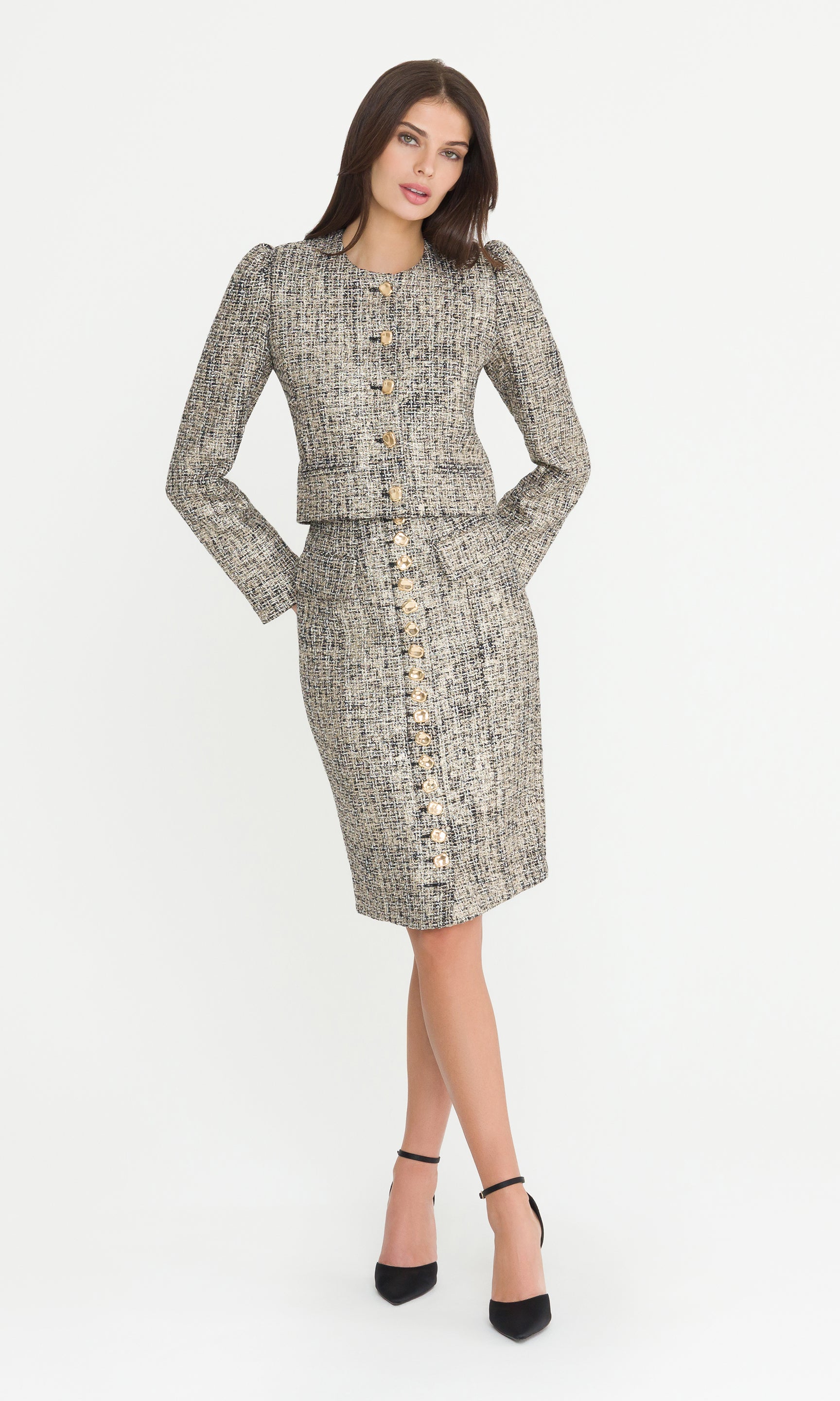 Full body image of model wearing a gold multi tweed skirt suit with a matching jacket