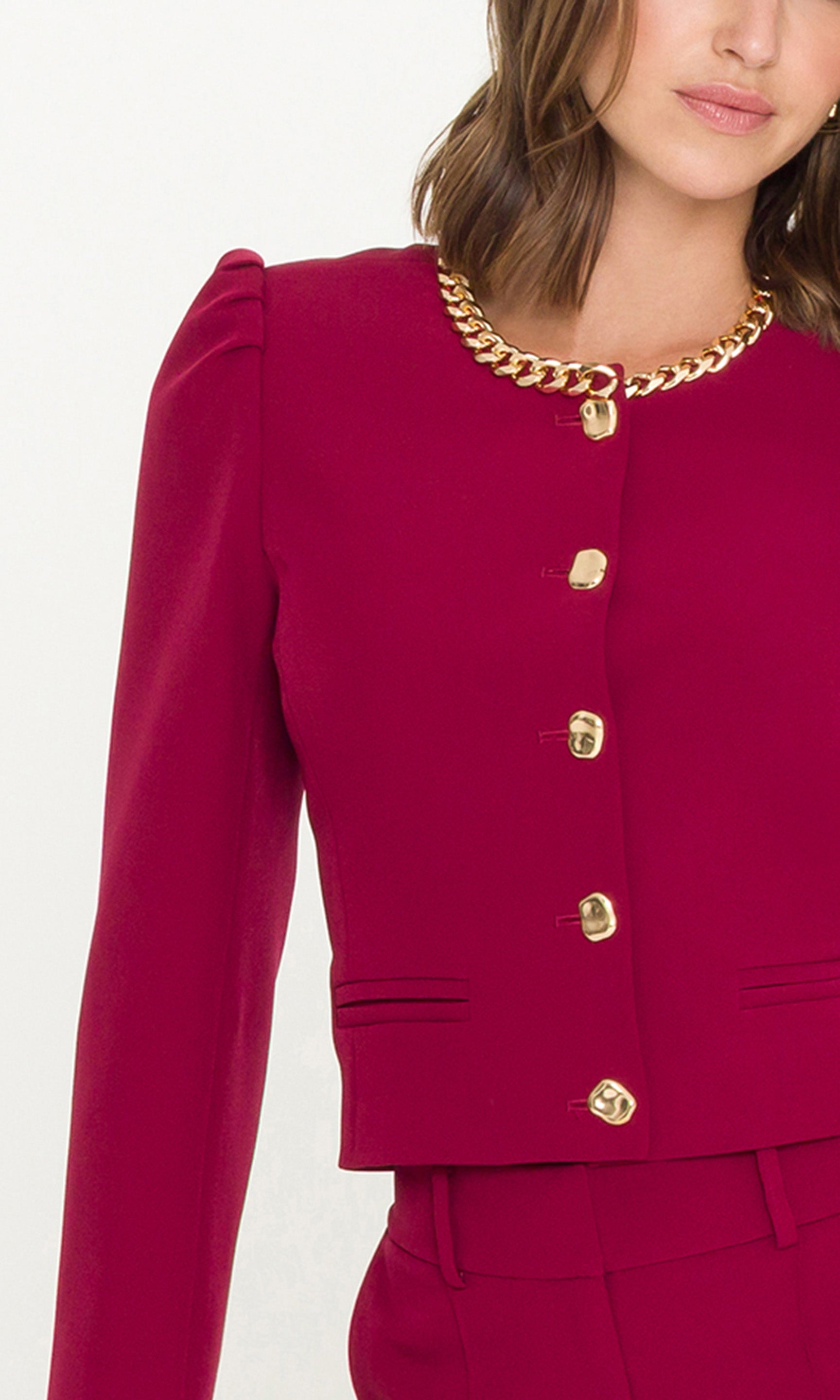 Close-up of woman wearing a red jacket with a chain neckline detail and gold buttons