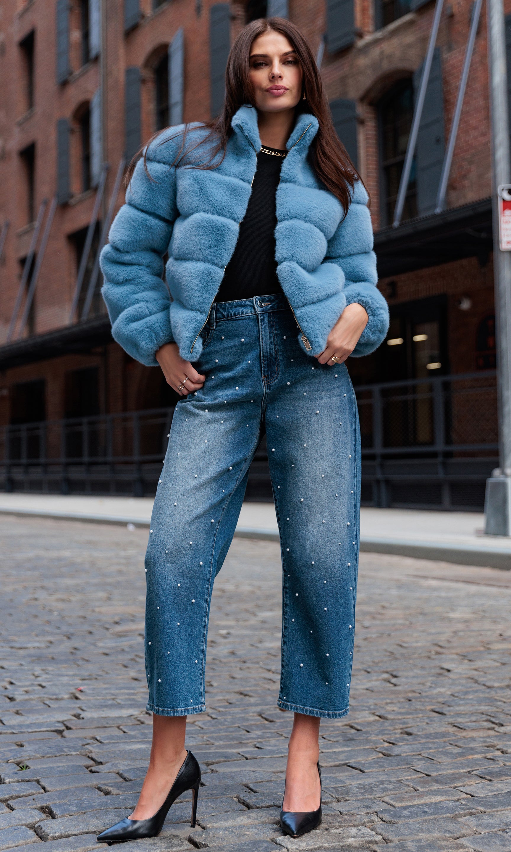 Woman wearing a blue puffer jacket and jeans on a city street.