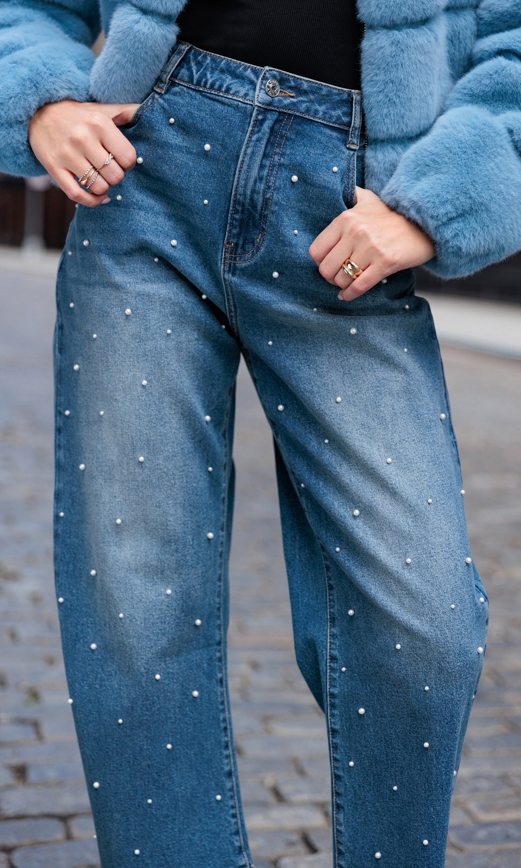 Blue jeans with pearl embellishments worn by a person in an urban setting