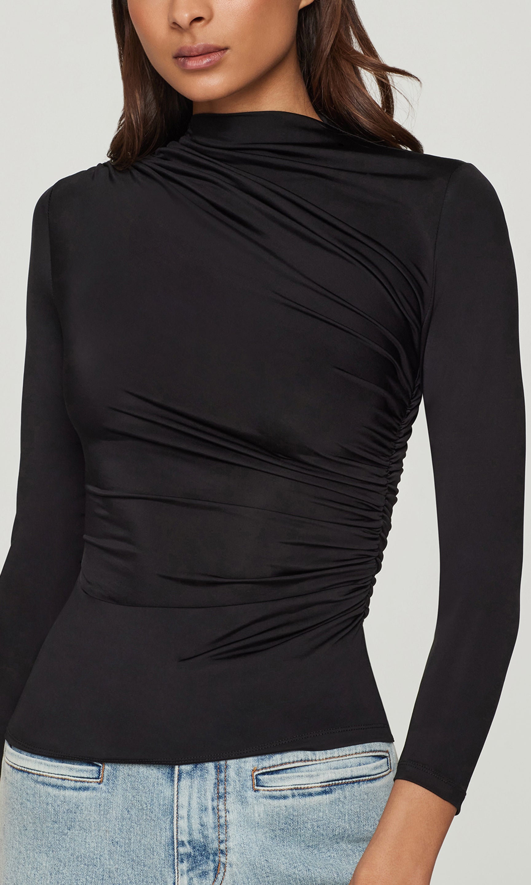 Close-up of black long-sleeve top worn by a person on a light gray background