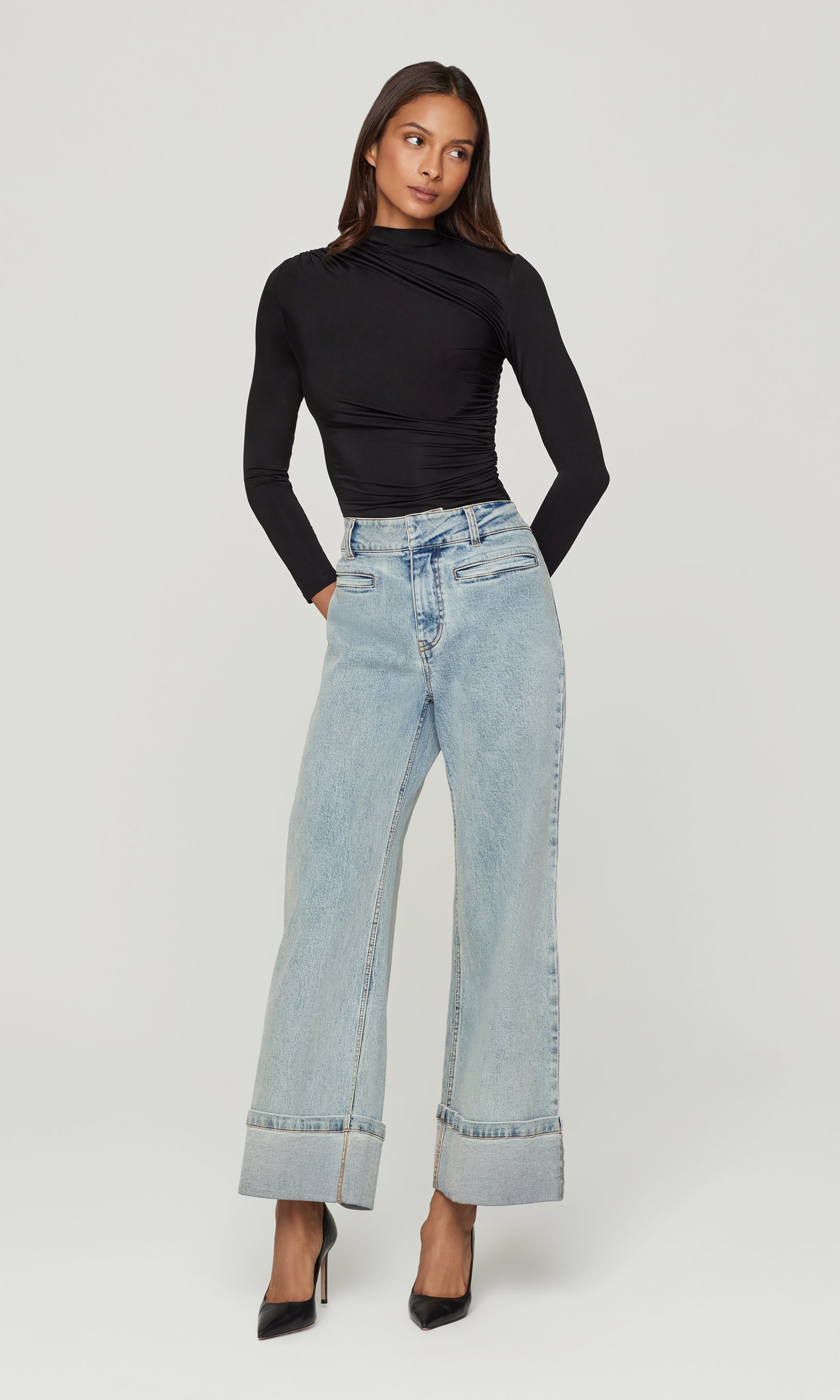 Woman wearing a black top and light blue jeans on a white background