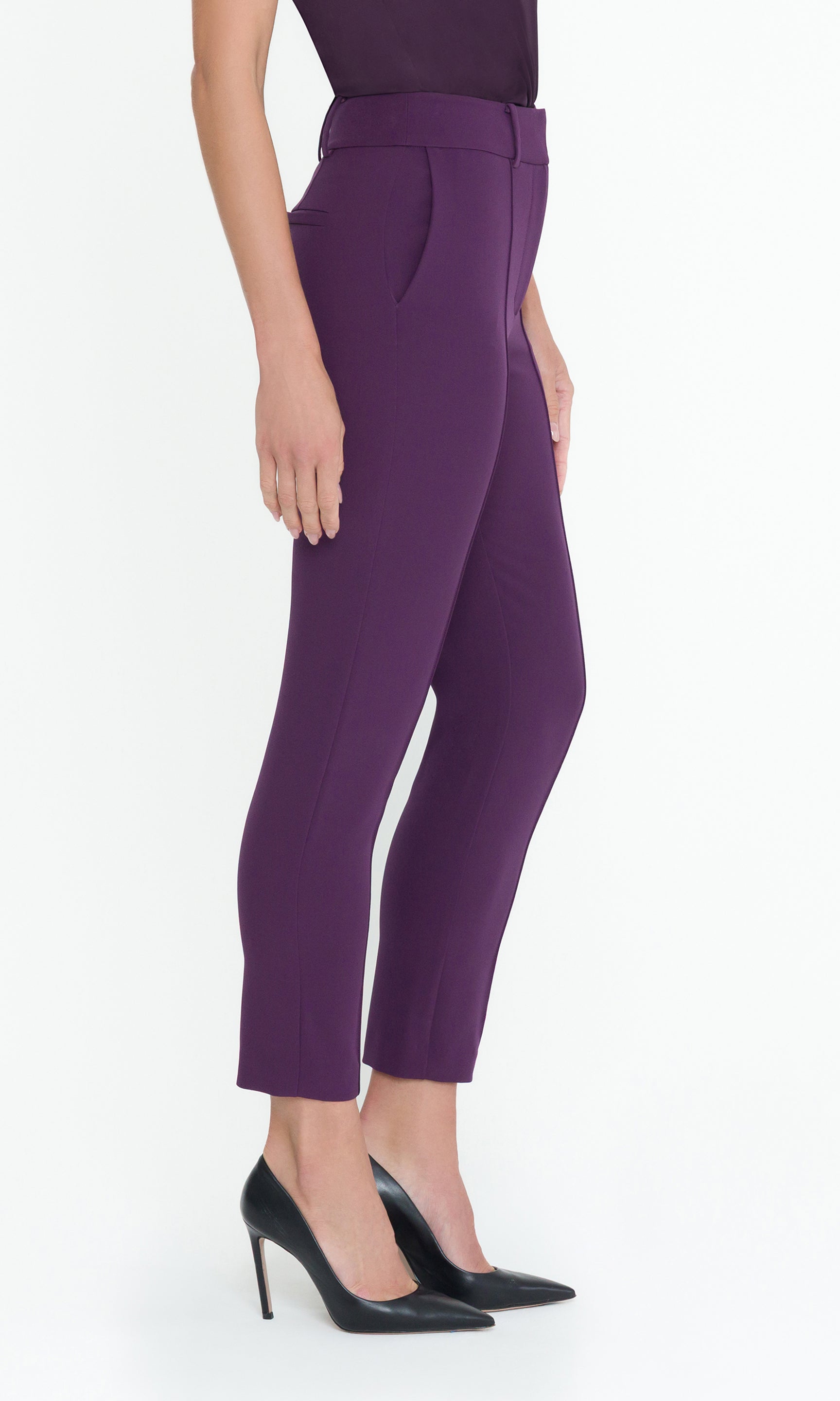 Side view of model wearing purple pants with a matching top on a white background