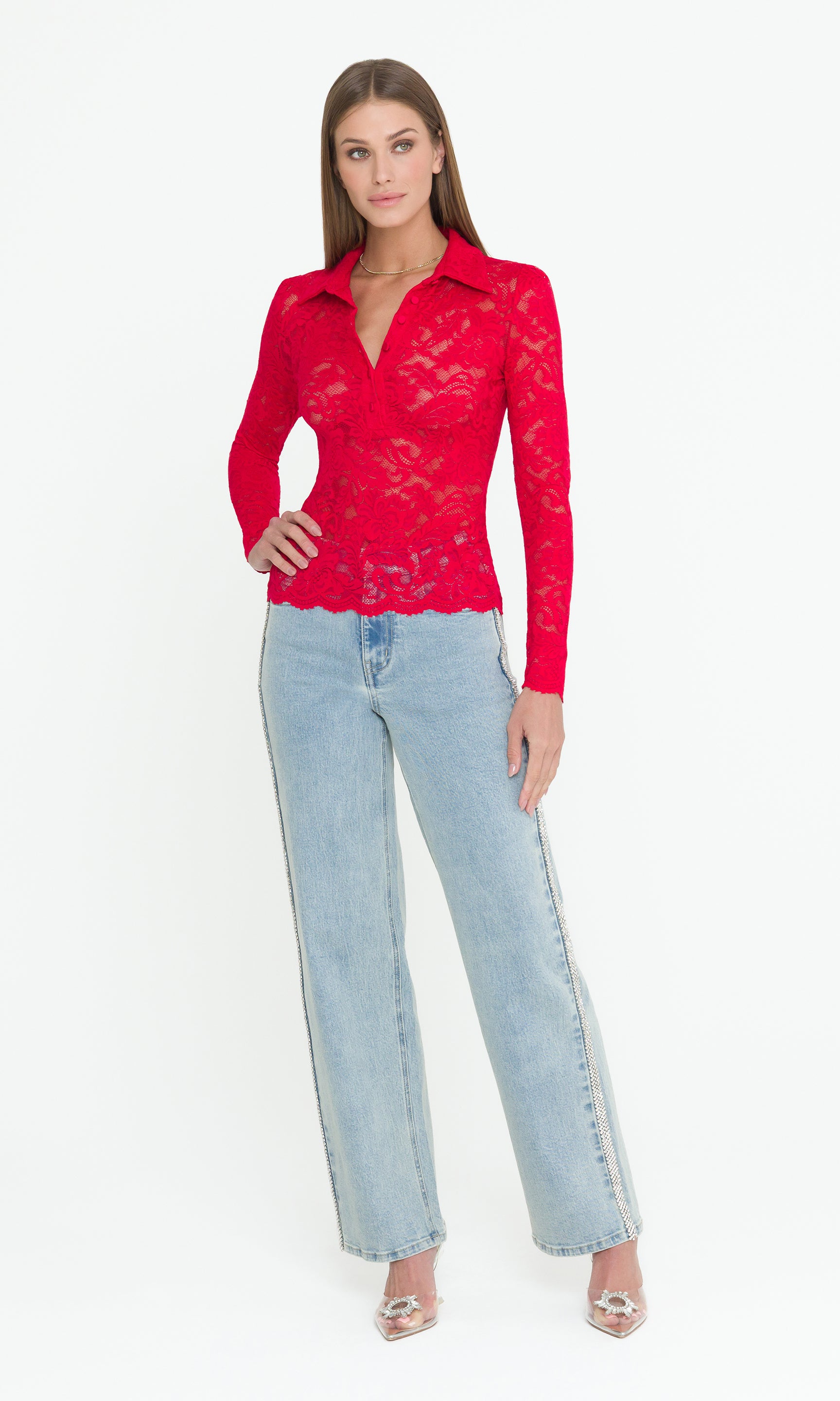 Full body image of woman wearing a long sleeve red lace top and light blue jeans on a white background