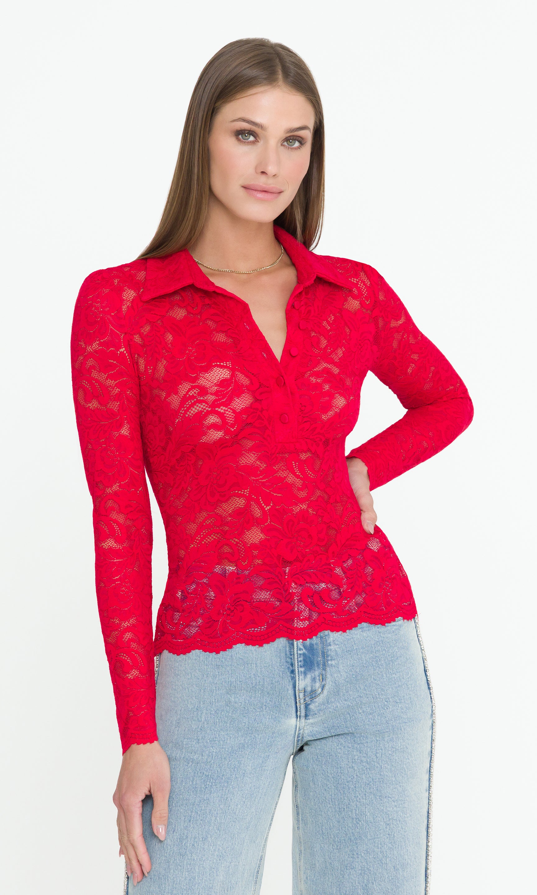 Woman wearing a red lace blouse and light blue jeans on a white background